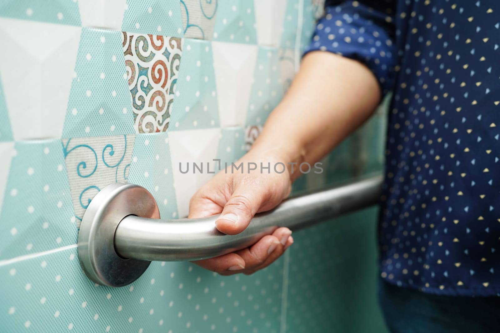 Asian woman patient use toilet support rail in bathroom, handrail safety grab bar, security in nursing hospital. by sweettomato