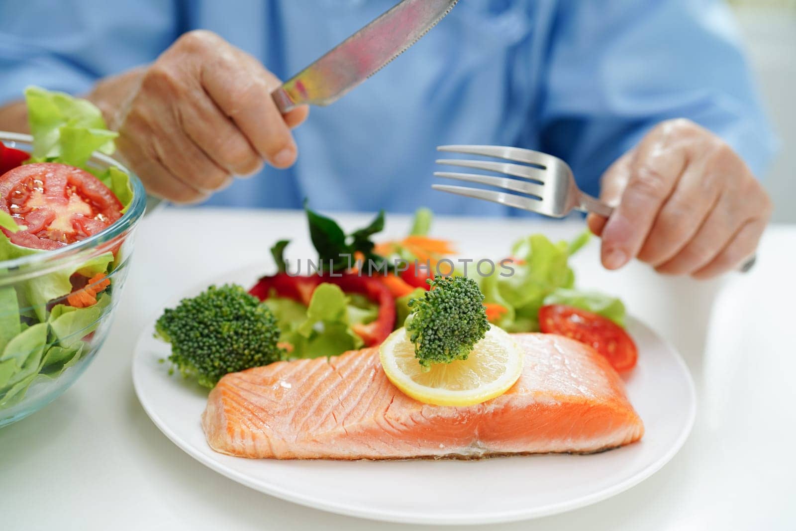 Asian elderly woman patient eating salmon stake and vegetable salad for healthy food in hospital. by sweettomato