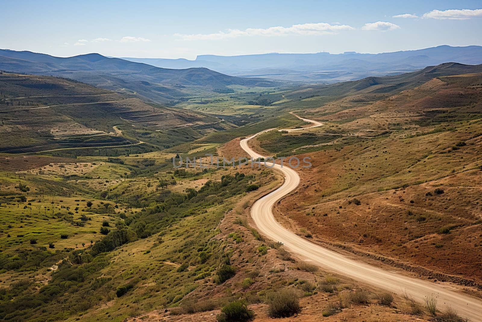 a dirt road in the middle of an open area with hills and mountains on either side, as seen from above