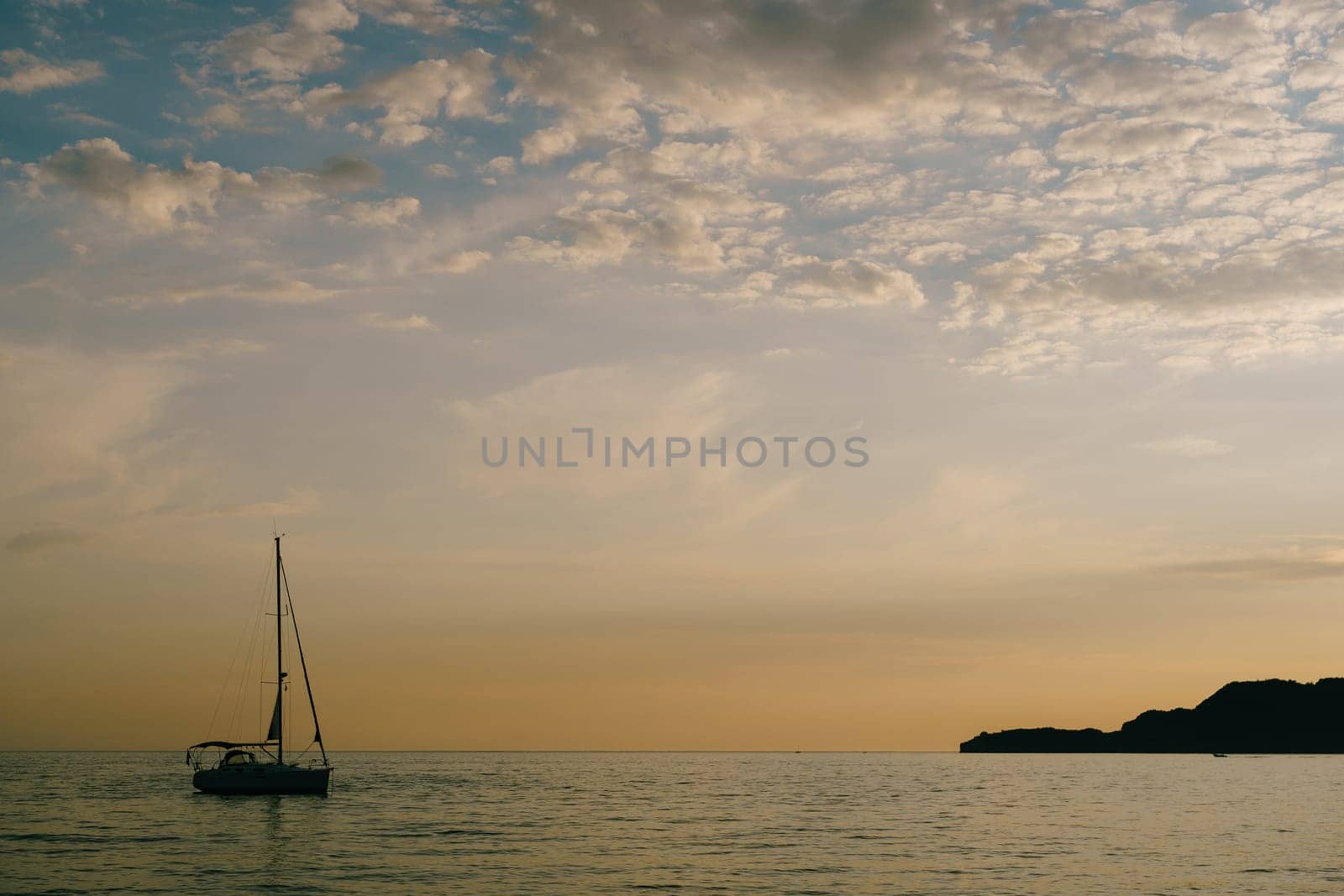 Sailing yacht sails on the sea at sunset by Nadtochiy