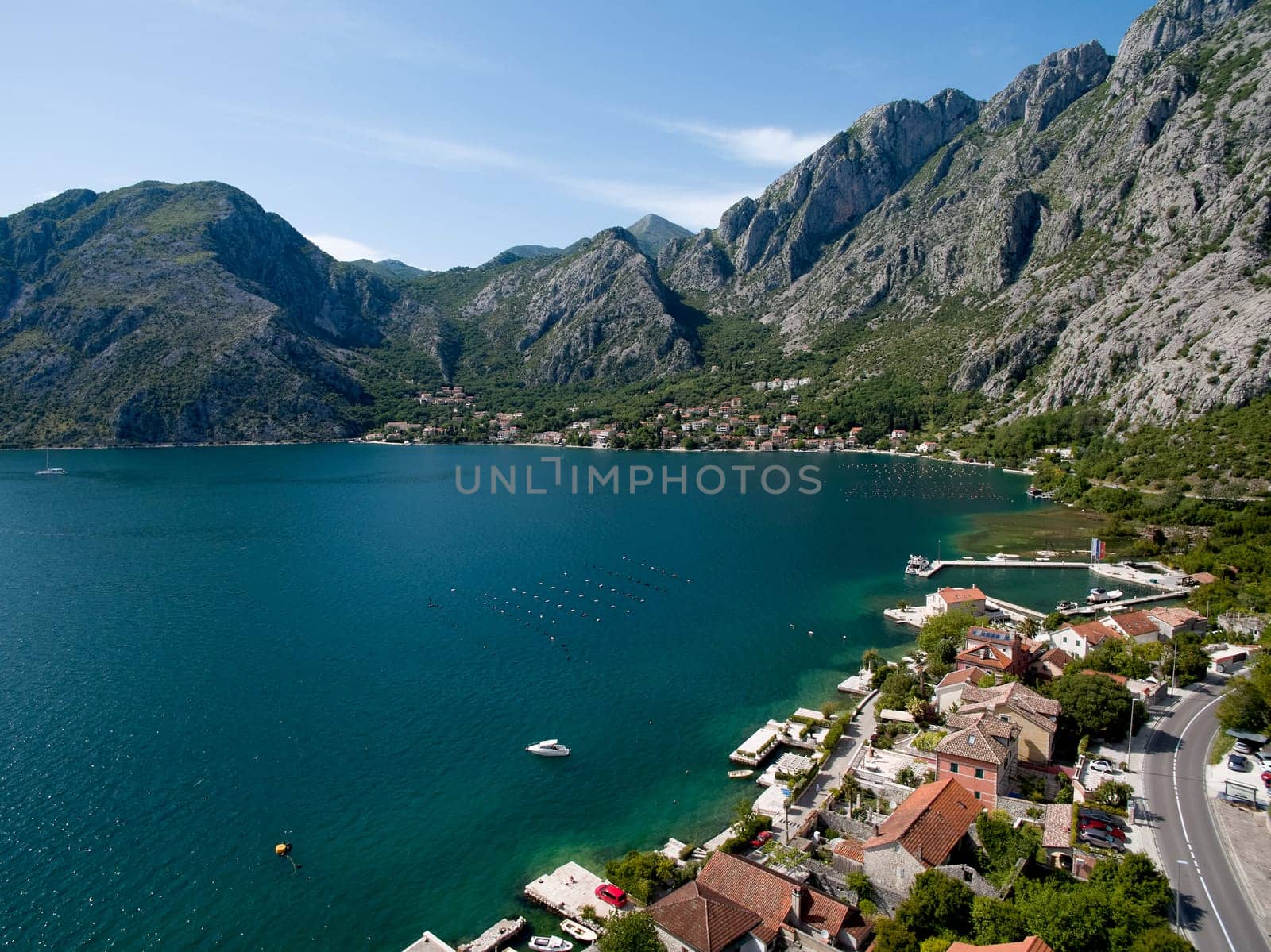 Red roofs of a resort town on the seashore at the foot of a mountain range. Drone by Nadtochiy