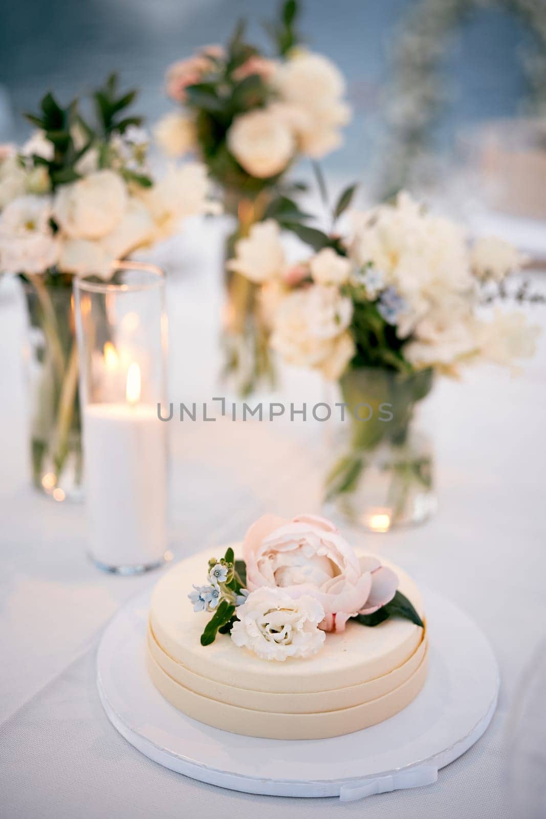 Wedding cake with floral decoration stands on a stand on the table by Nadtochiy