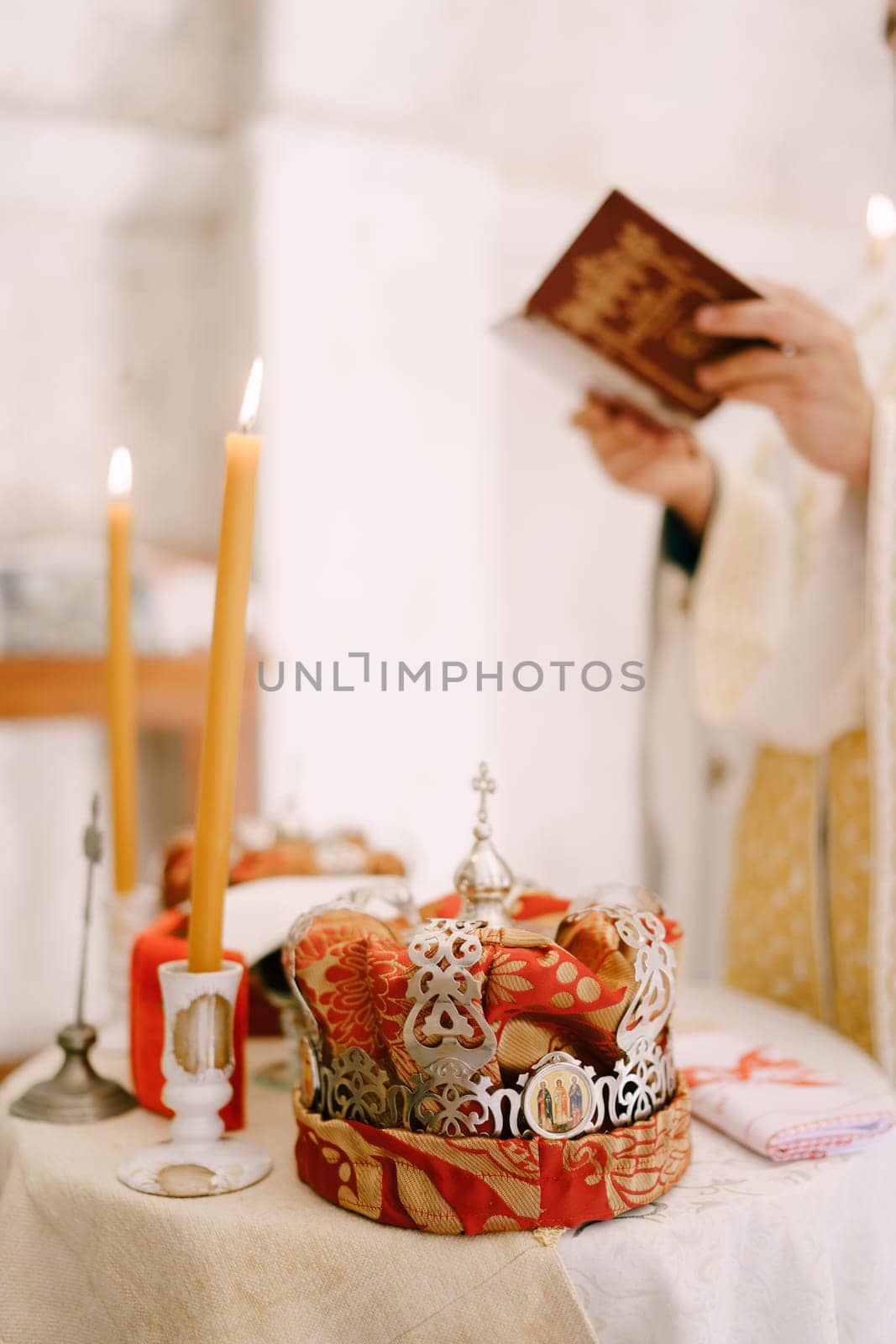 Priest reads the bible near the table with lit candles and wedding crowns. Cropped. High quality photo