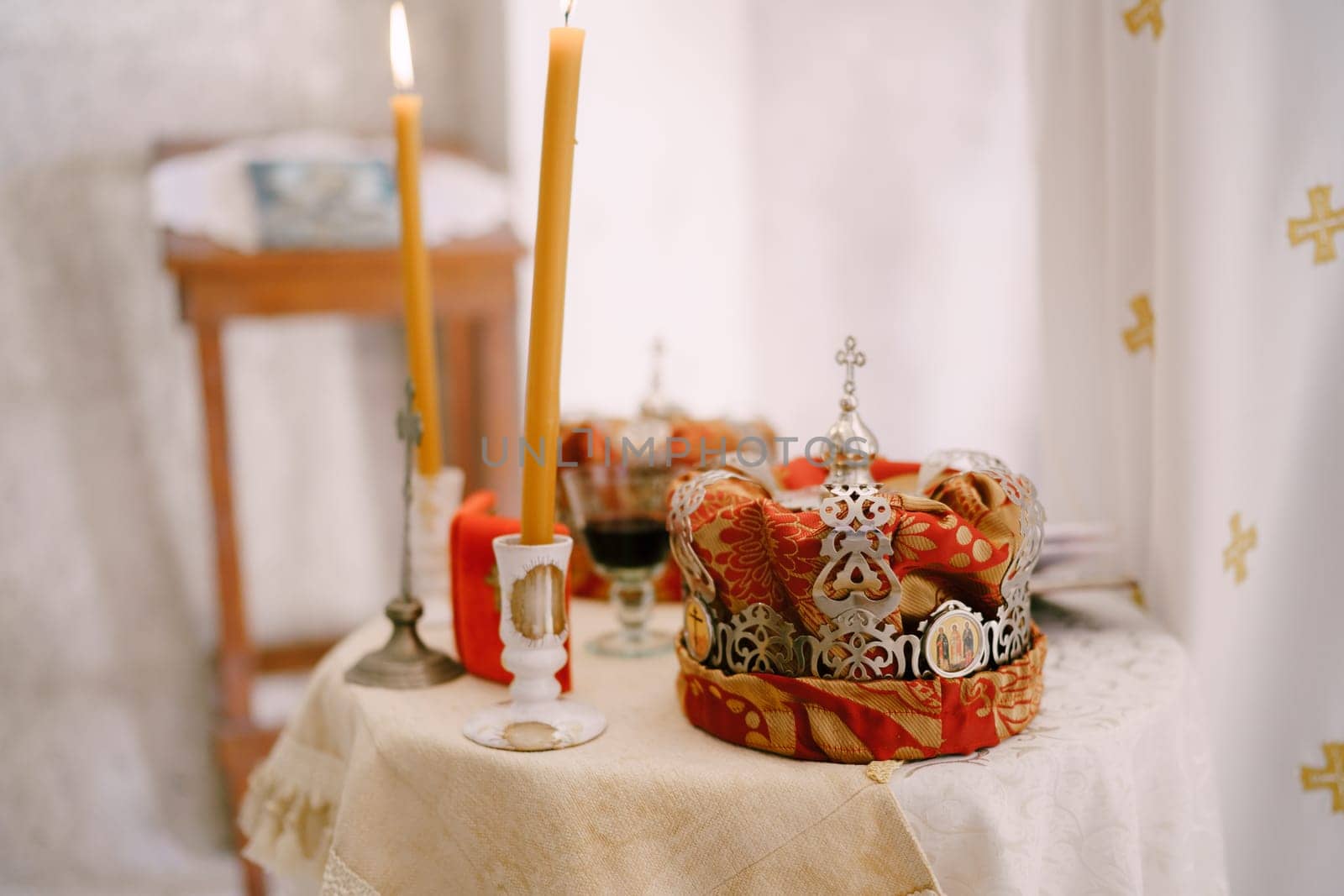 Lighted candles in candlesticks on the table near the wedding crowns in the church. High quality photo
