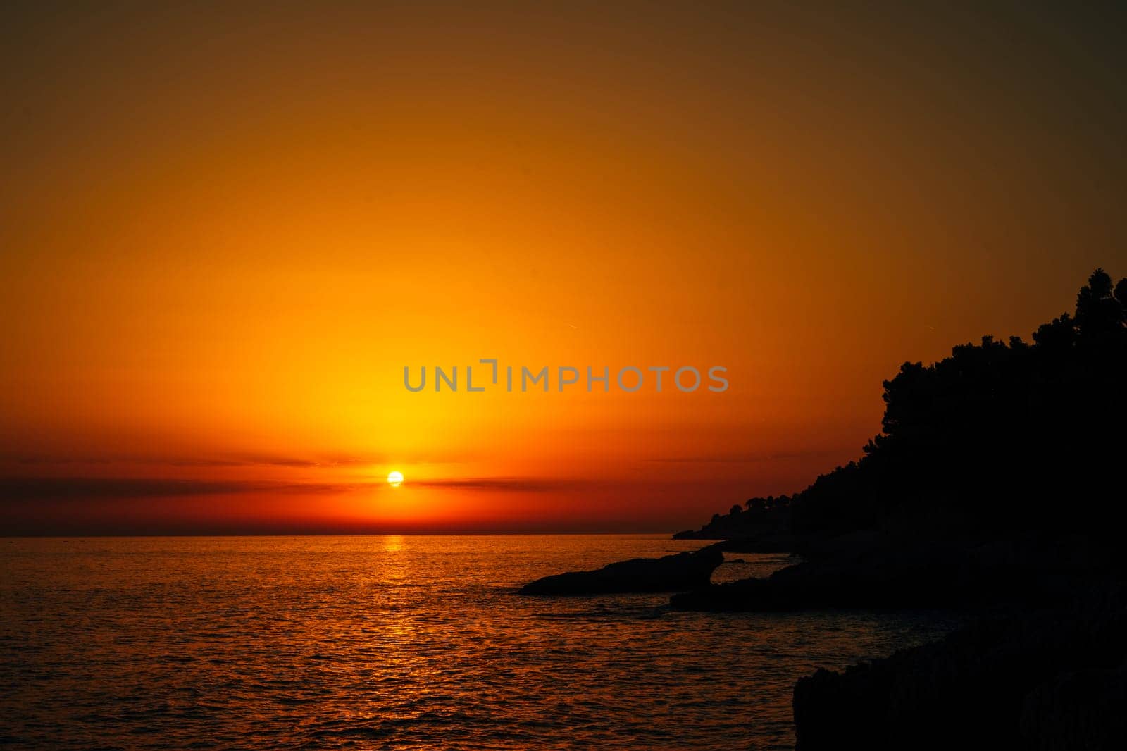 Sunset over the sea and dark hilly shore. High quality photo