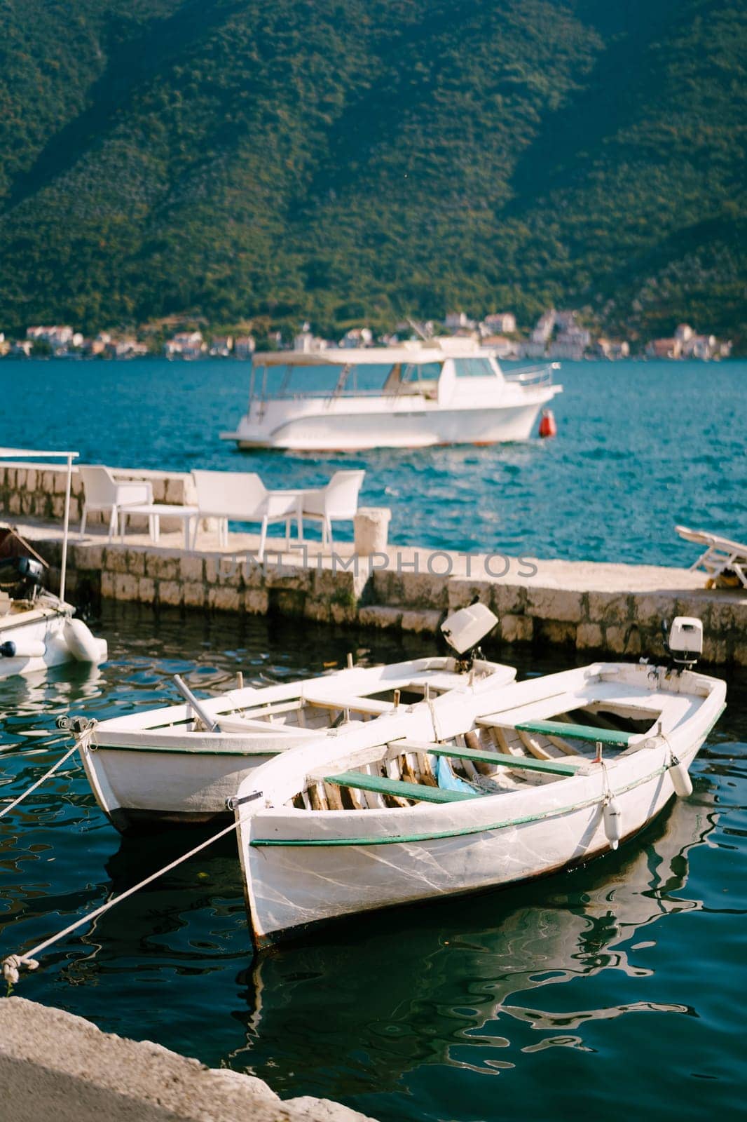 Fishing boats are moored to the shore between two piers. High quality photo