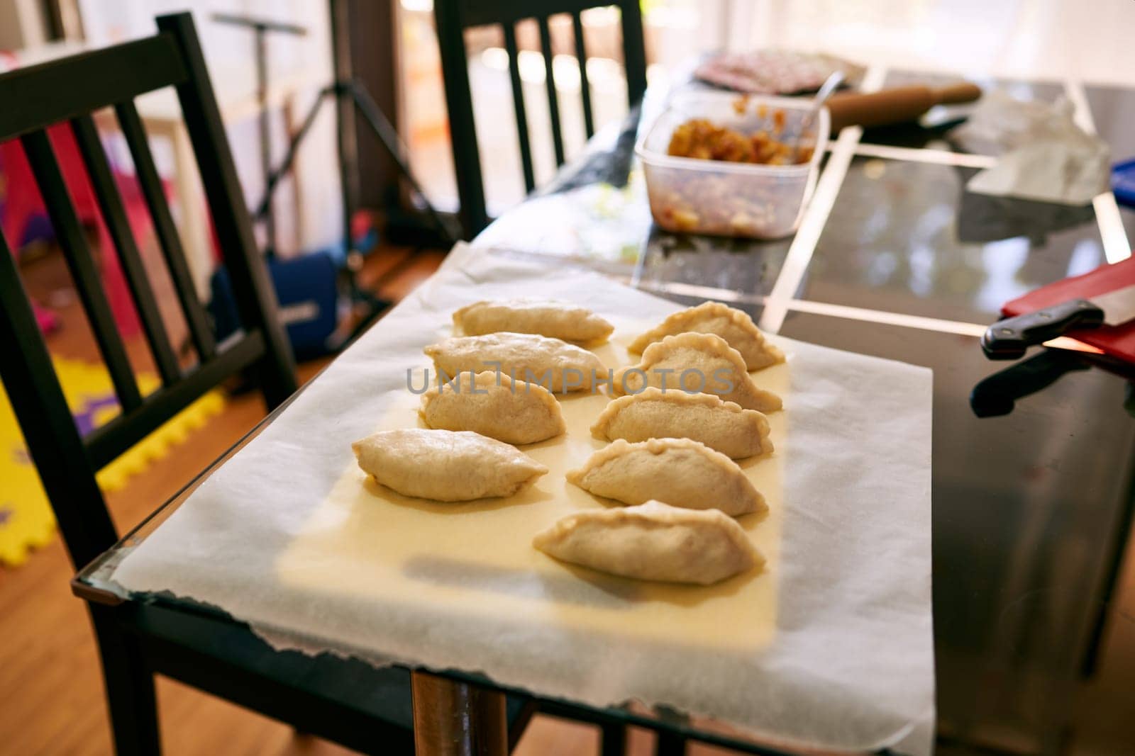 Raw stuffed buns lie on baking paper on the table. High quality photo