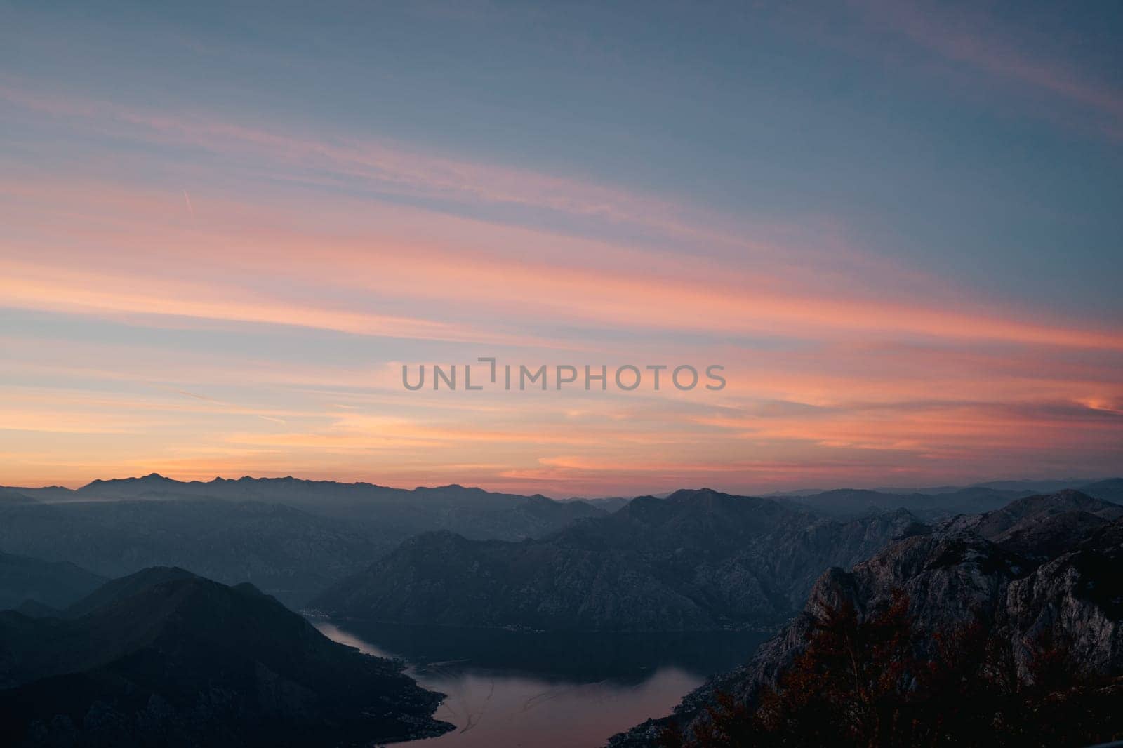 Sunset sky over a mountain range by the bay by Nadtochiy