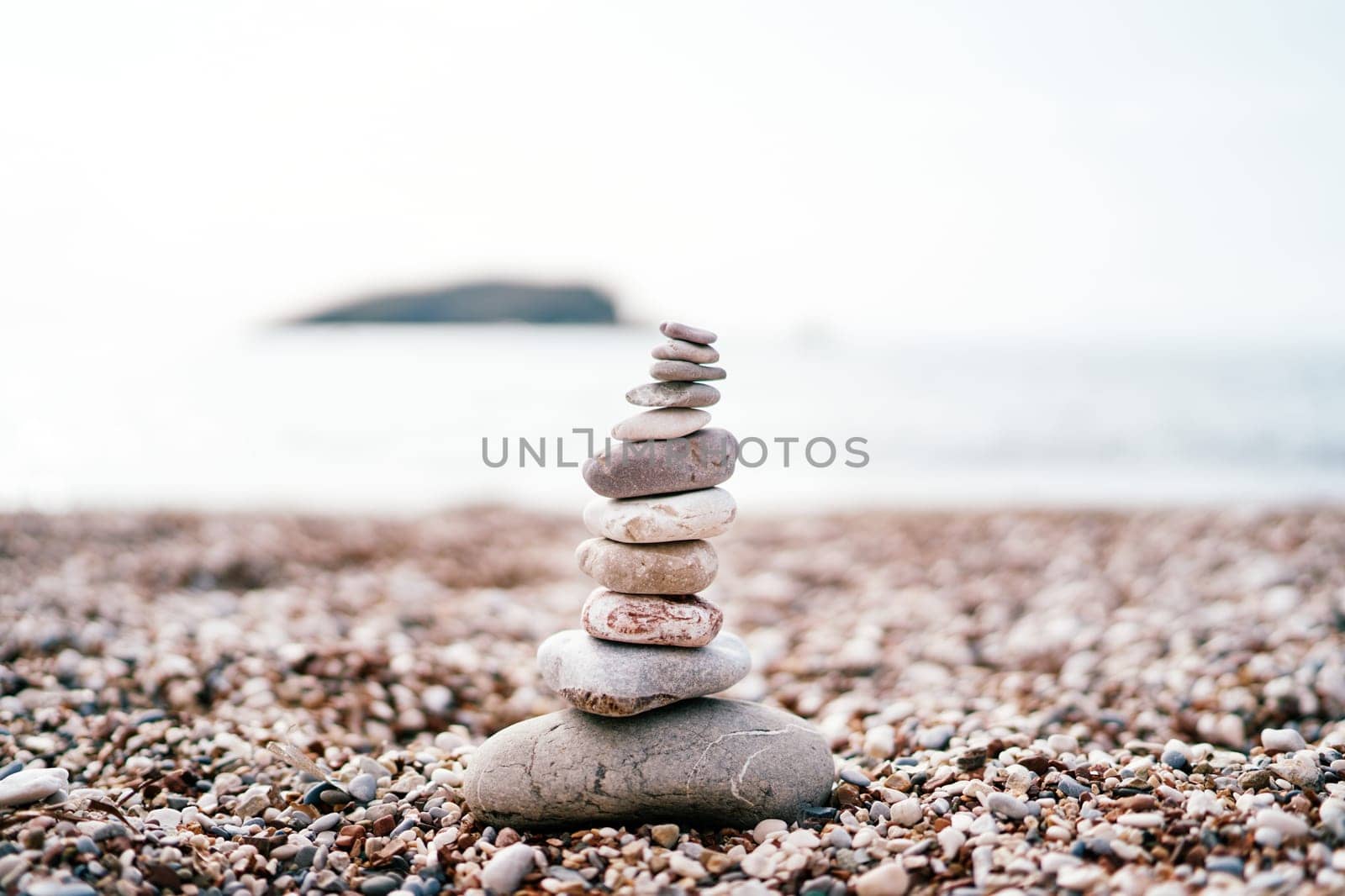 Cairn stands on a pebble beach by the sea. High quality photo