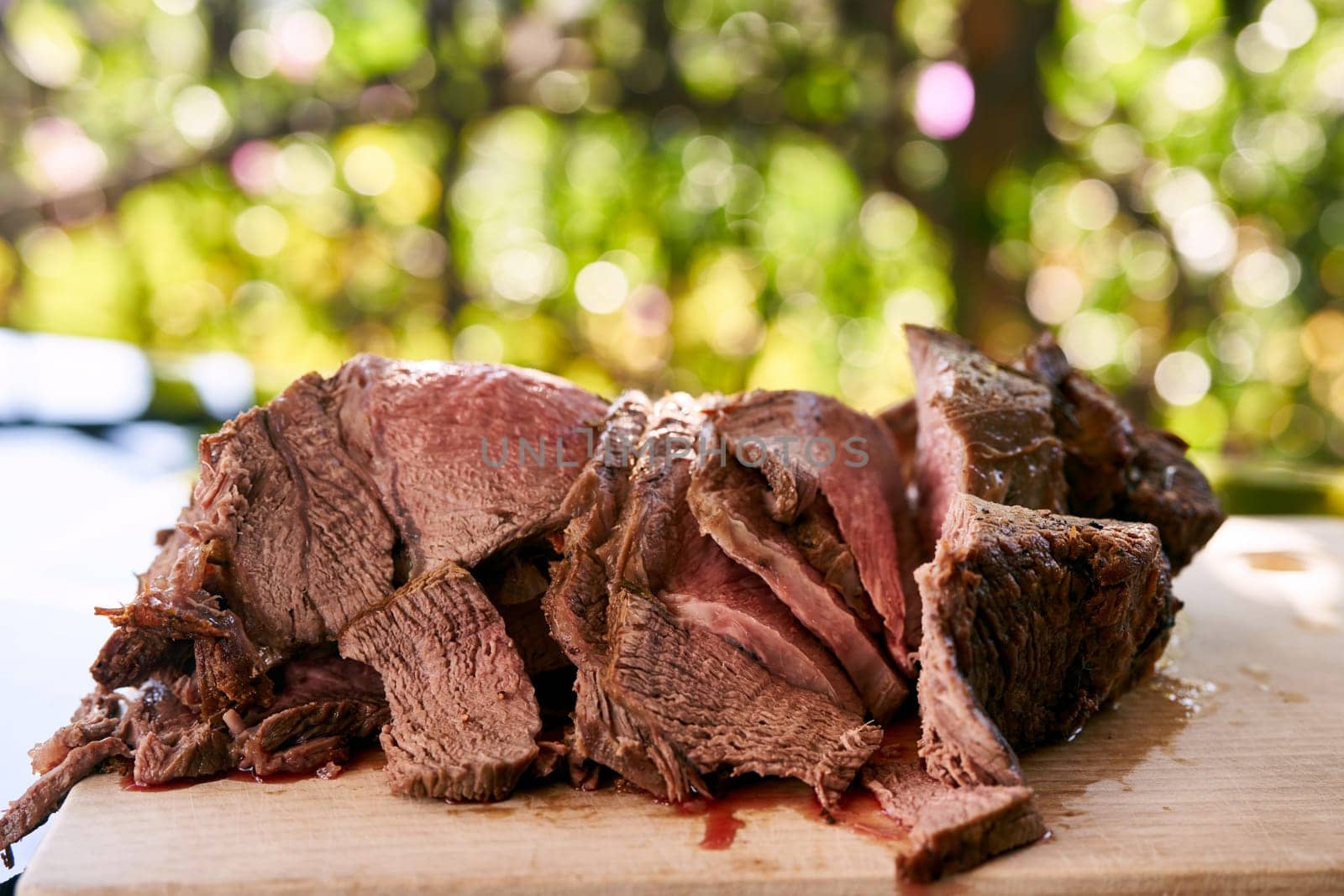 Slices of juicy roast beef lie on a cutting board on a glass table. High quality photo