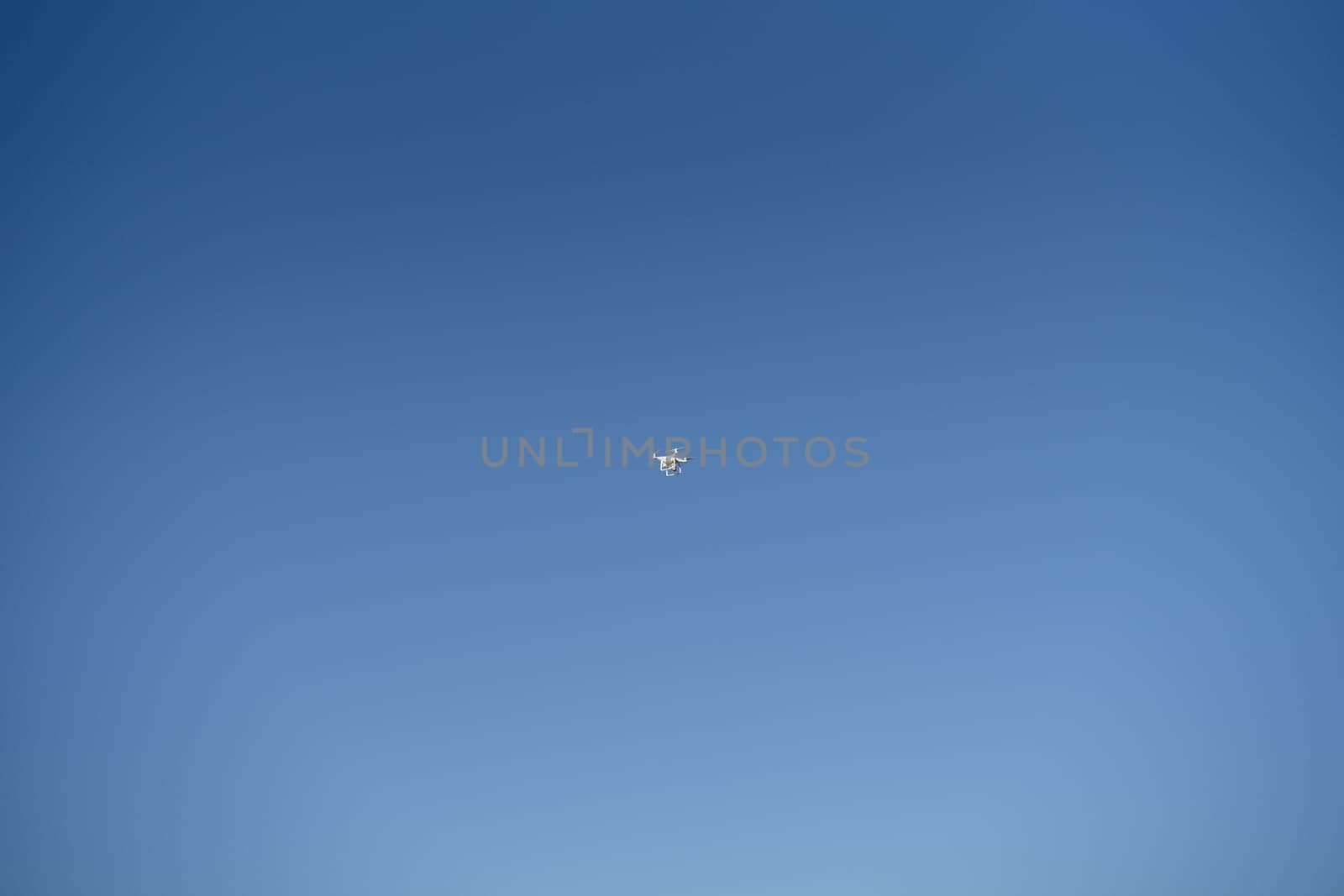 White drone soars in the blue sky. Bottom view. High quality photo