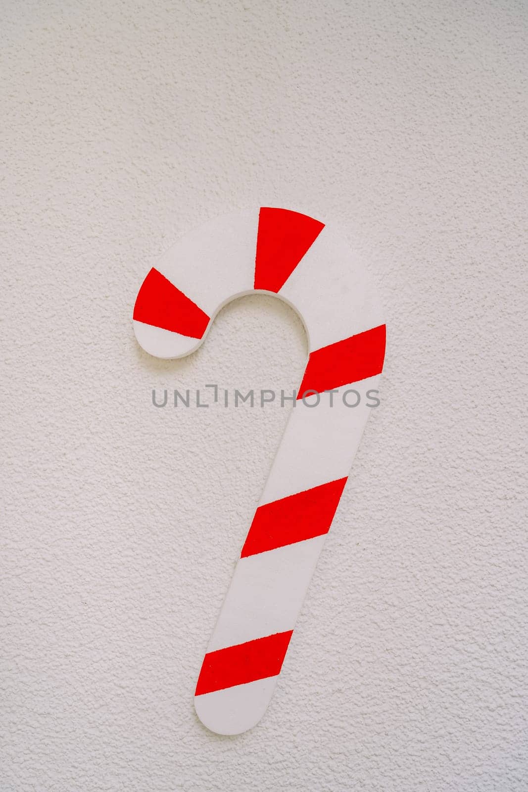 Christmas toy in the shape of a striped candy cane on a white background. High quality photo
