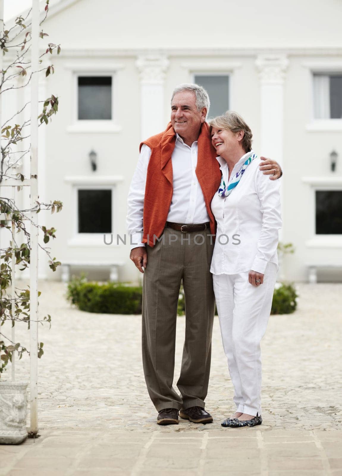 Hug, smile and old couple outside hotel, villa and luxury hospitality on retirement vacation together. Marriage, travel and holiday accommodation, senior man and woman embrace in courtyard in Italy