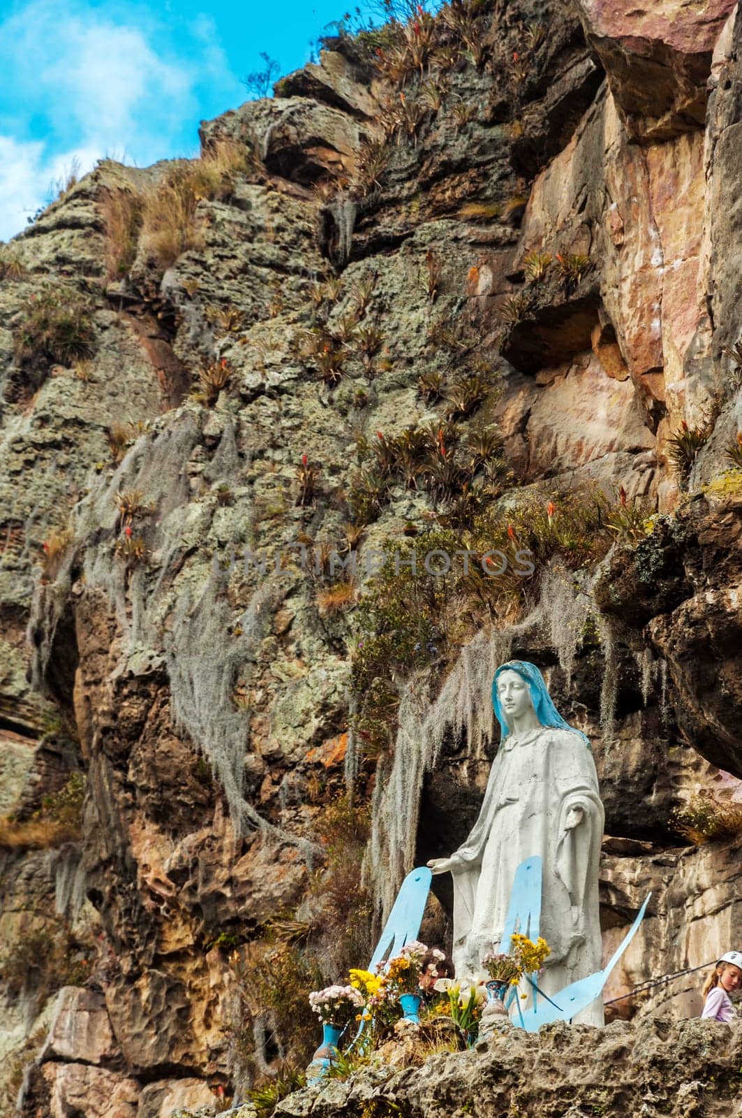 Statue of the Virgin Mary with a dramatic cliff rising behind it