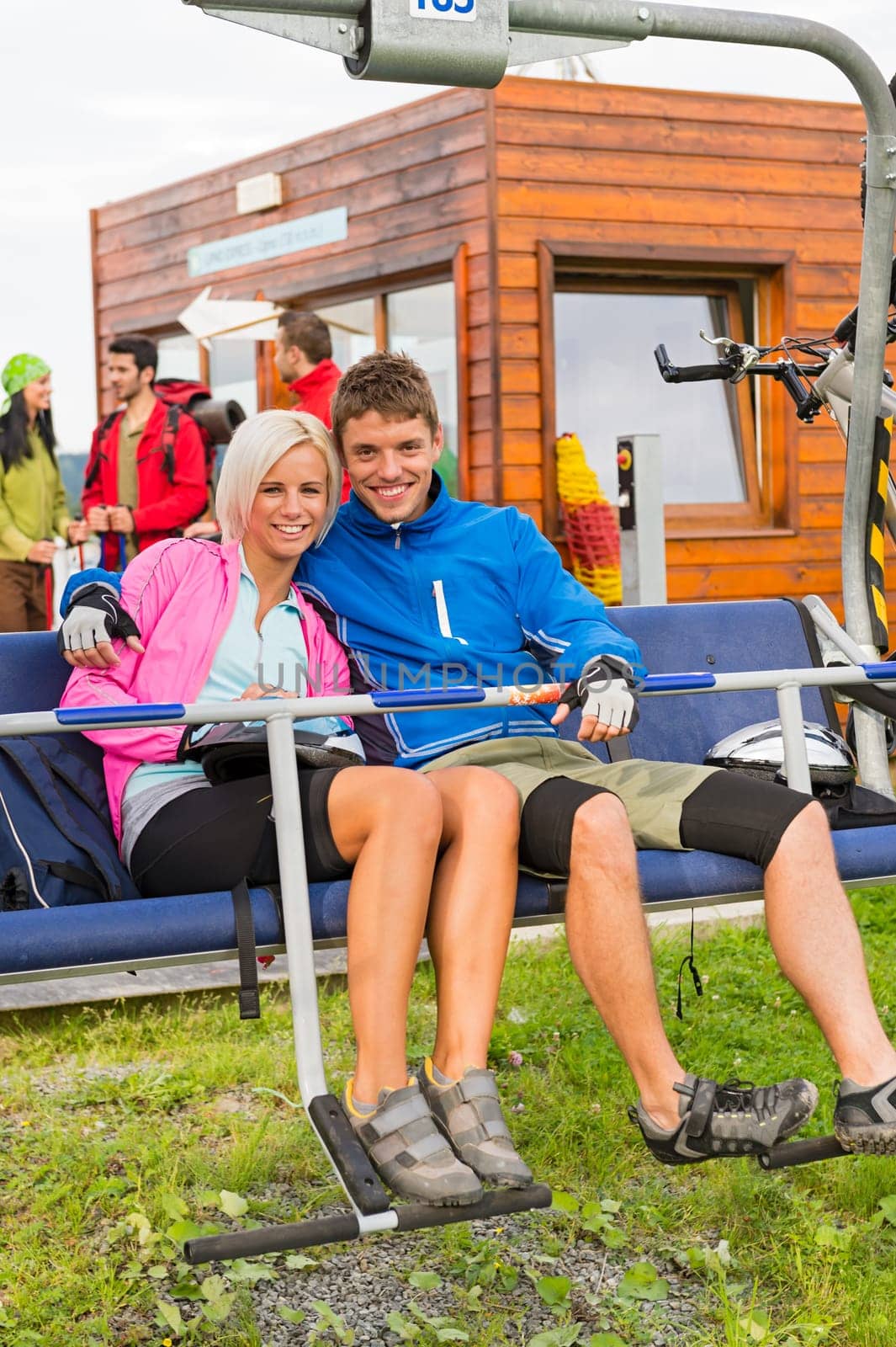 Smiling hugging couple sitting and waiting on chair-lift