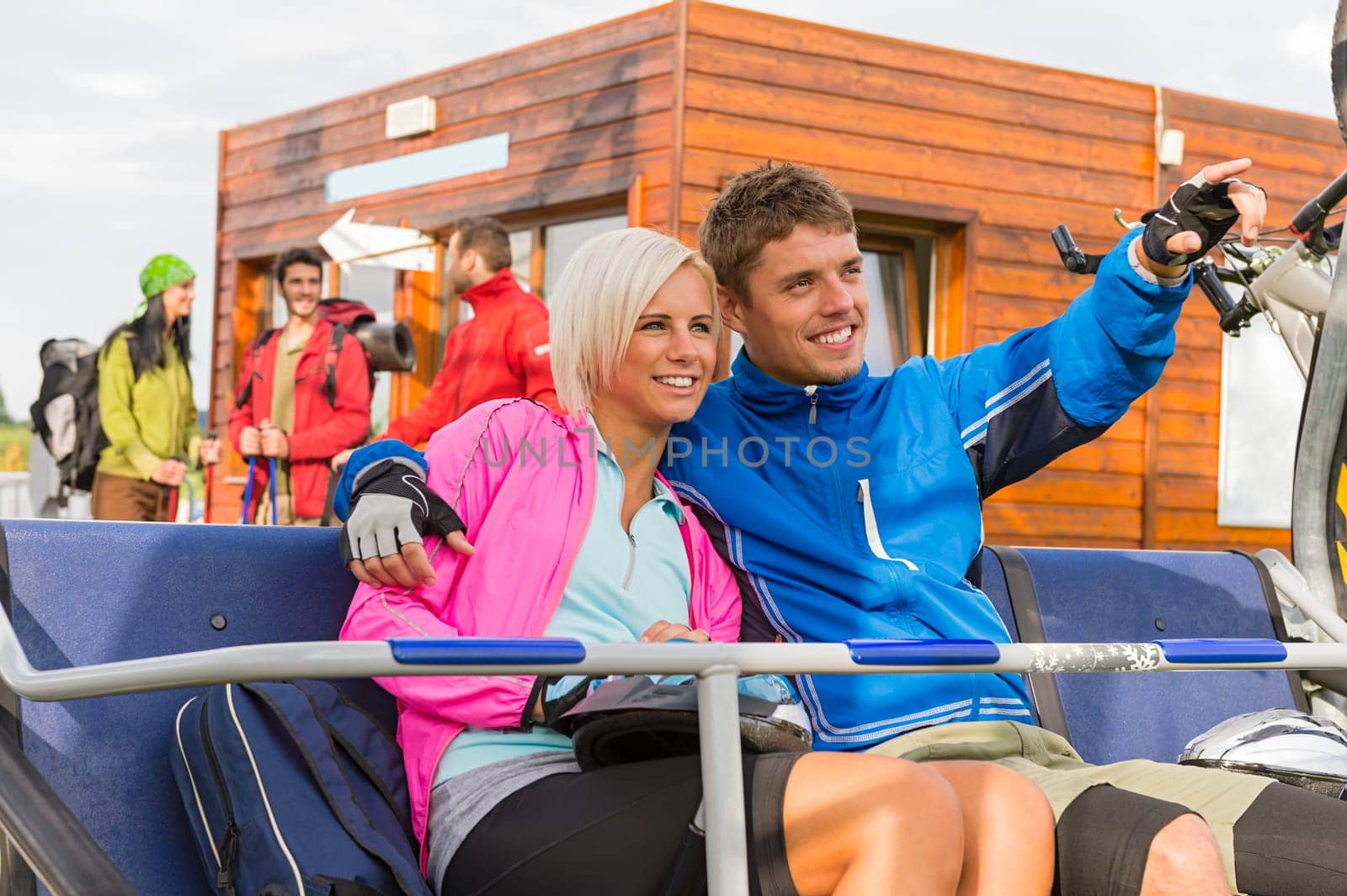 Cheerful couple sitting on chair lift man pointing