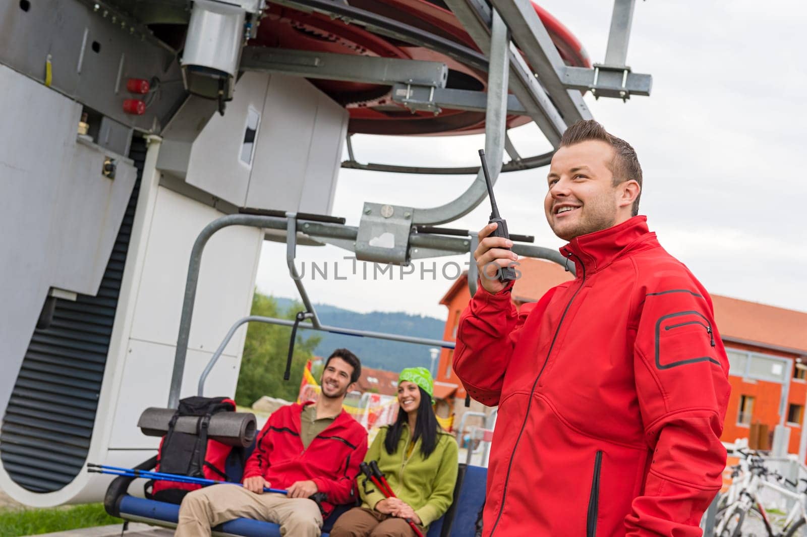 Man in red coat using radio starting chair lift