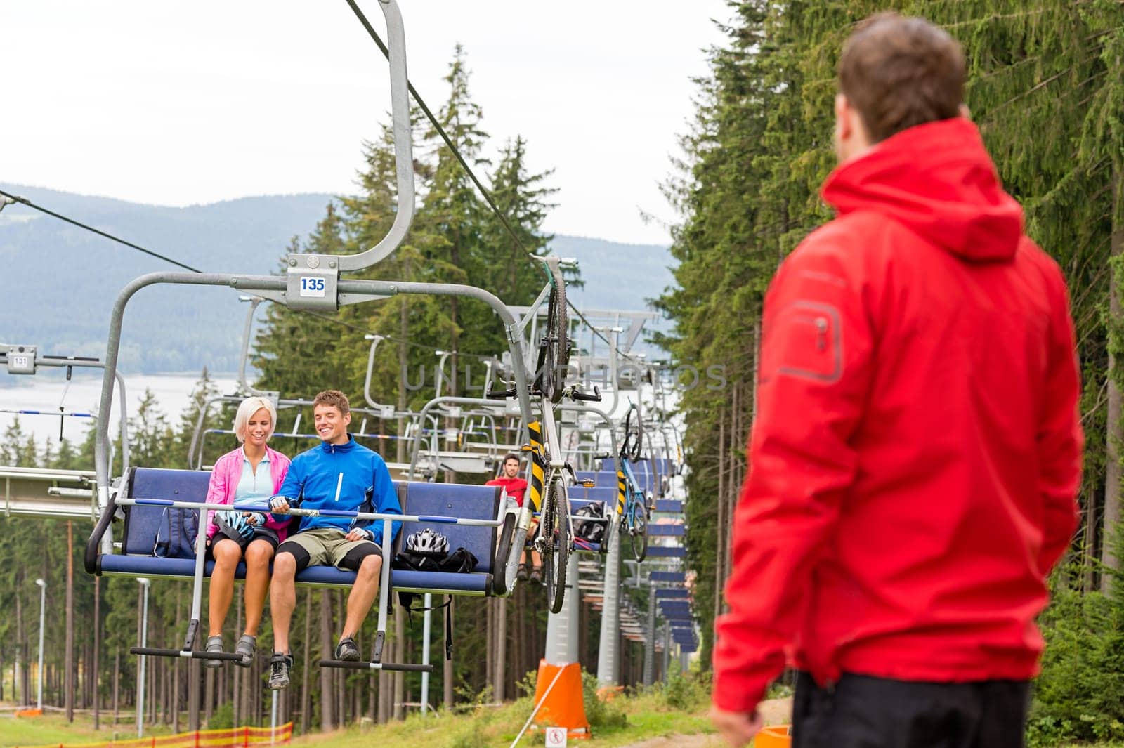 Young couple enjoying chair lift in the wood holiday resort