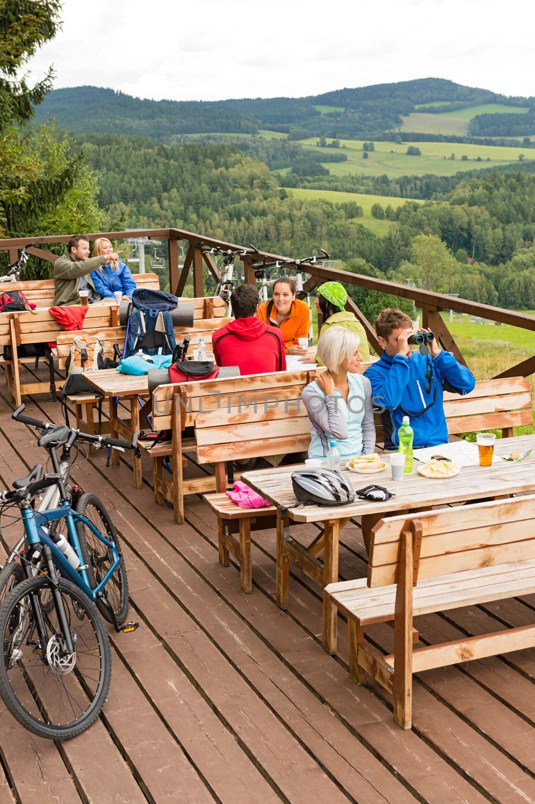 Tired hikers sitting at rest area man looking through binoculars
