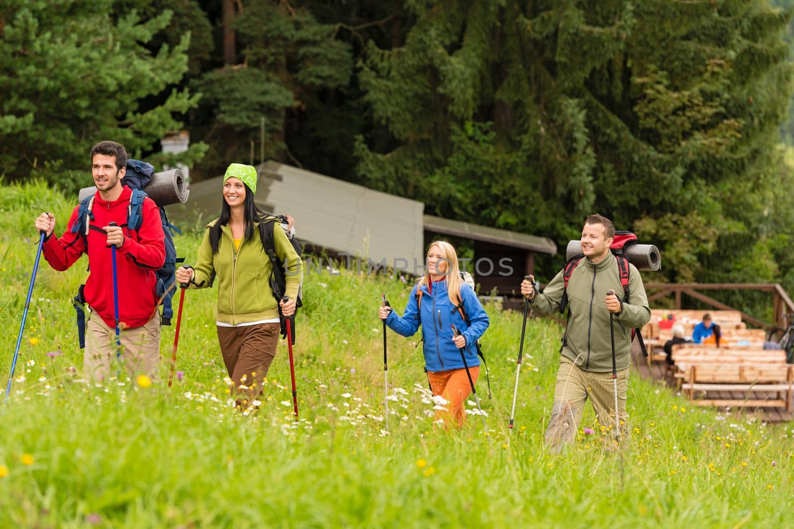 Smiling young people trekking in nature landscape with sticks
