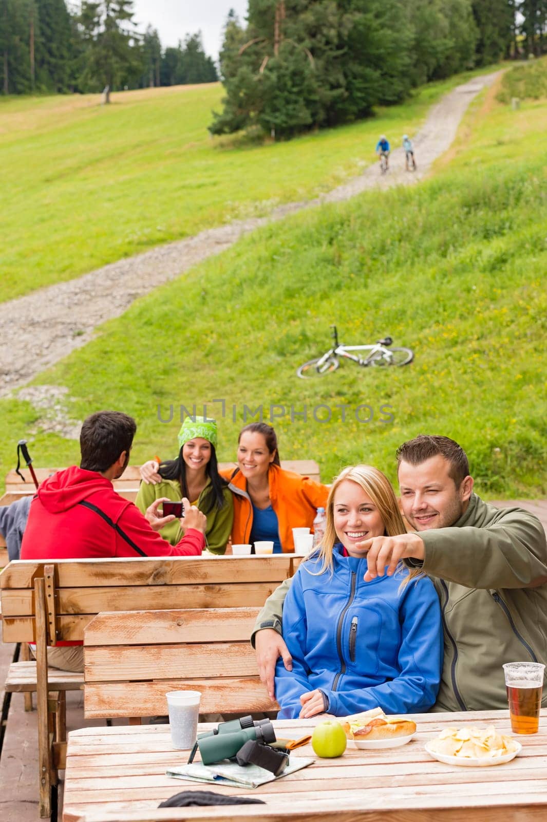 Young sporty tourists resting on wooden bench nature pointing direction