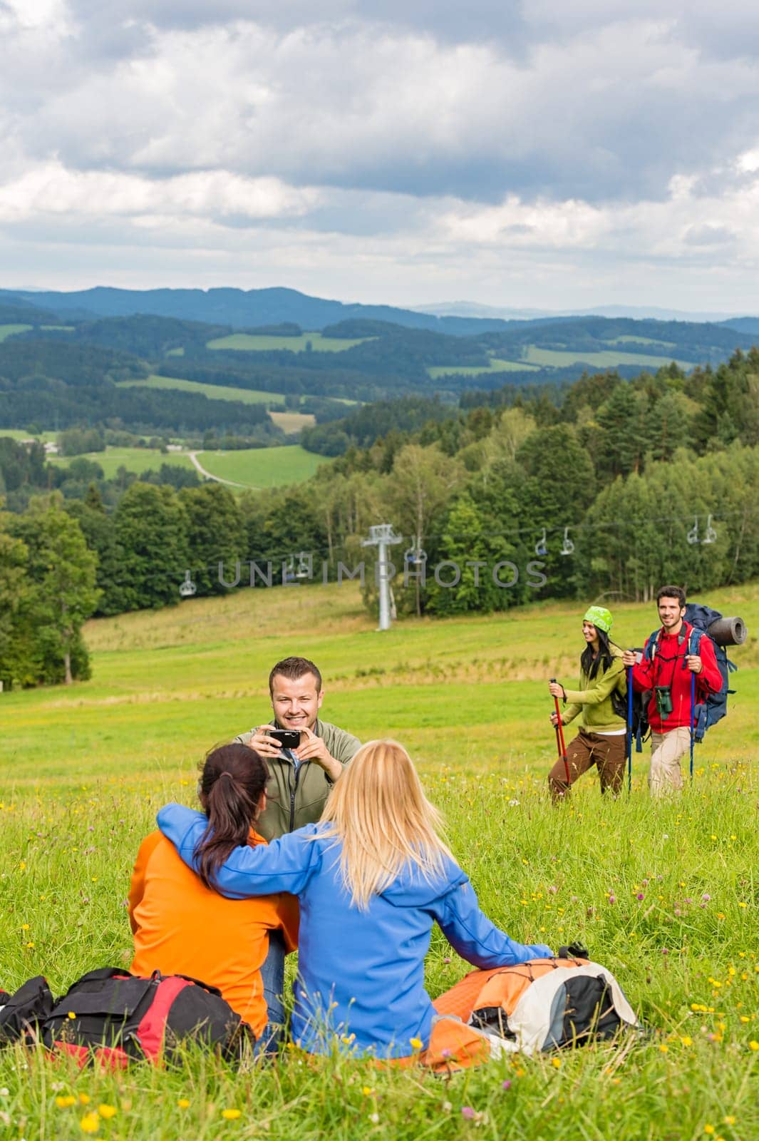 Young hiking friends resting and taking photograph in scenic view