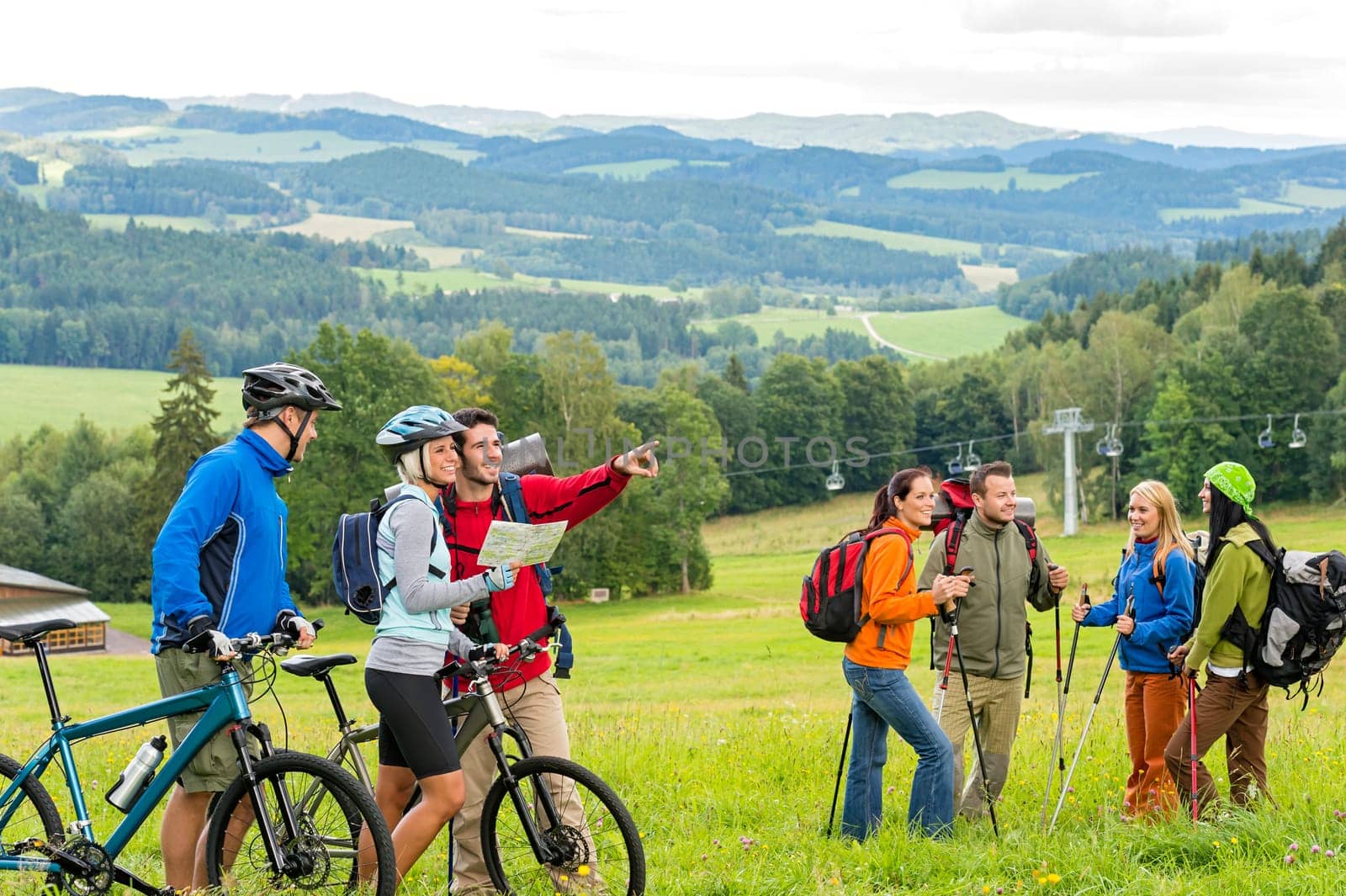 Hikers helping cyclists following track in nature landscape