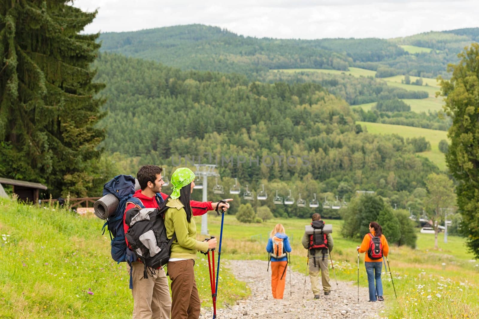 Young hikers with sticks enjoying scenic view on the mountain