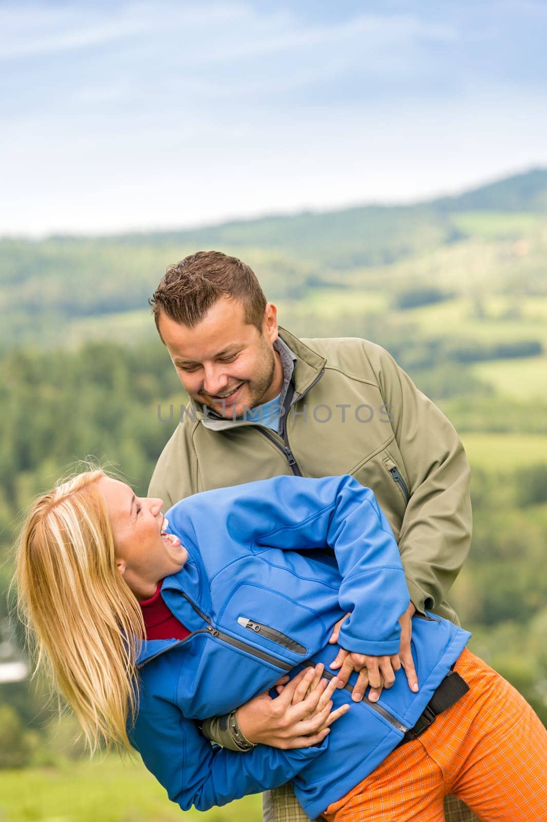 Sporty young couple hugging in front of scenic landscape