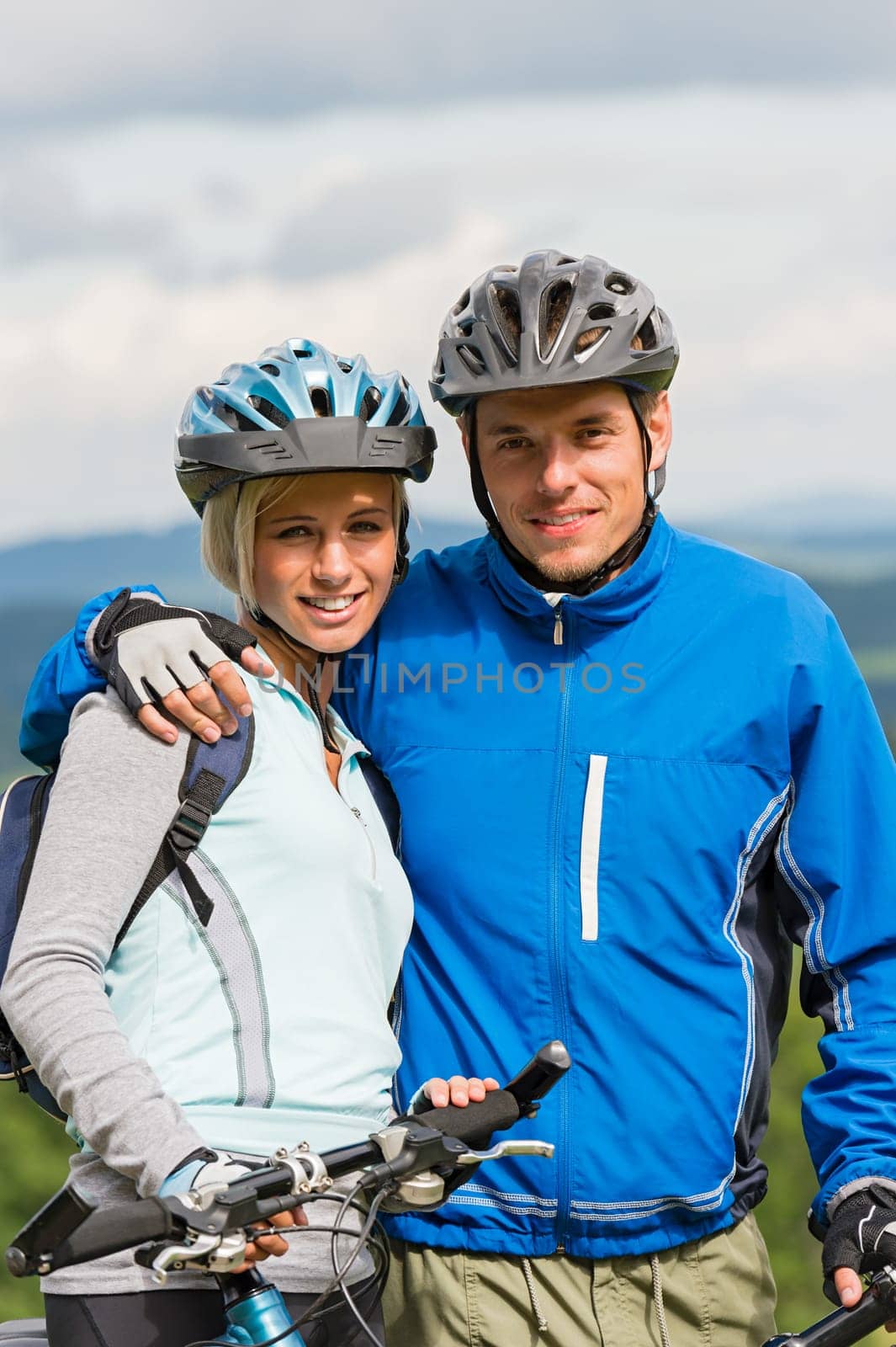Young smiling sporty couple with bicycles in helmet