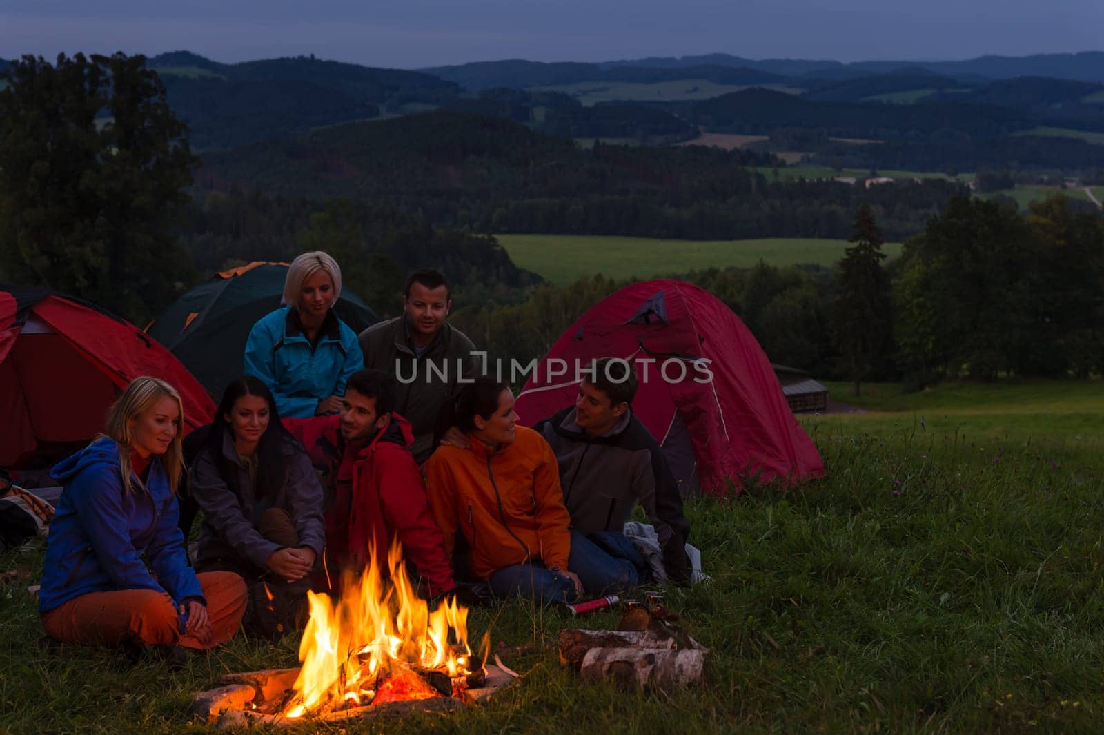 During night camping friends setting fire beside tents