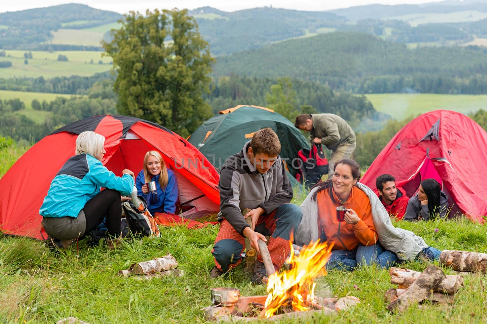 Group of young students spending weekend together in tents campfire