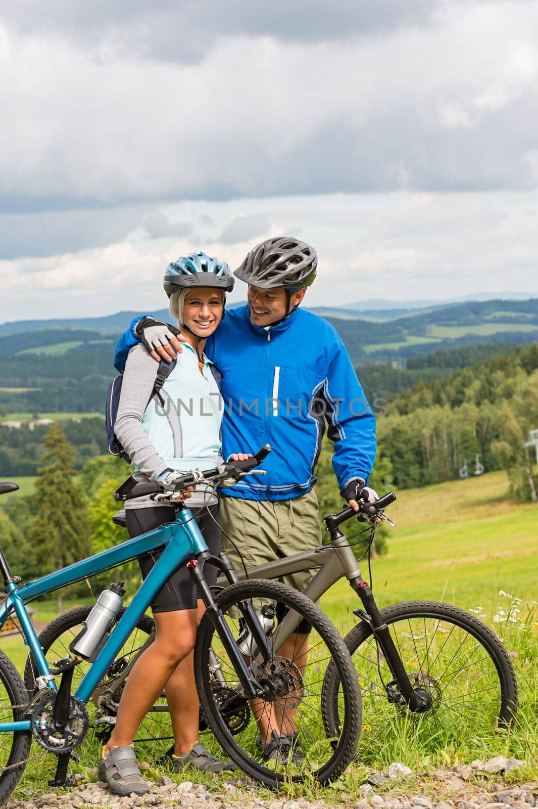 Young cuddling cyclists with mountain bikes during summer weekend
