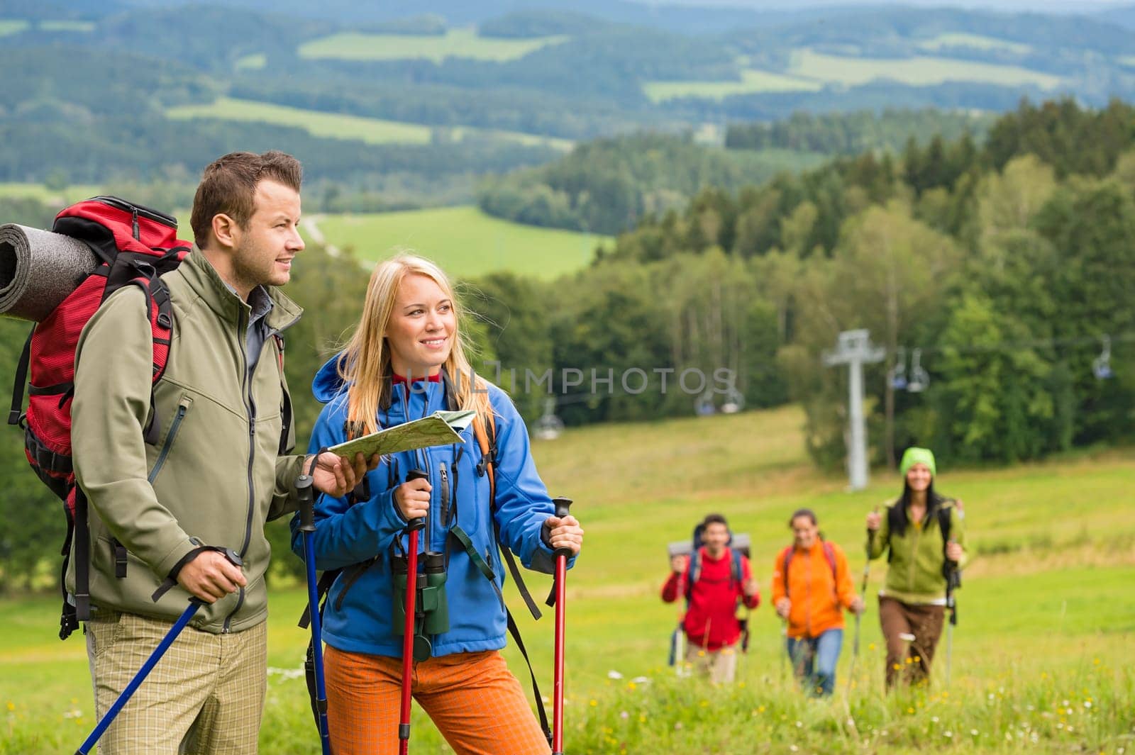 Young hiker friends reading map in natural landscape