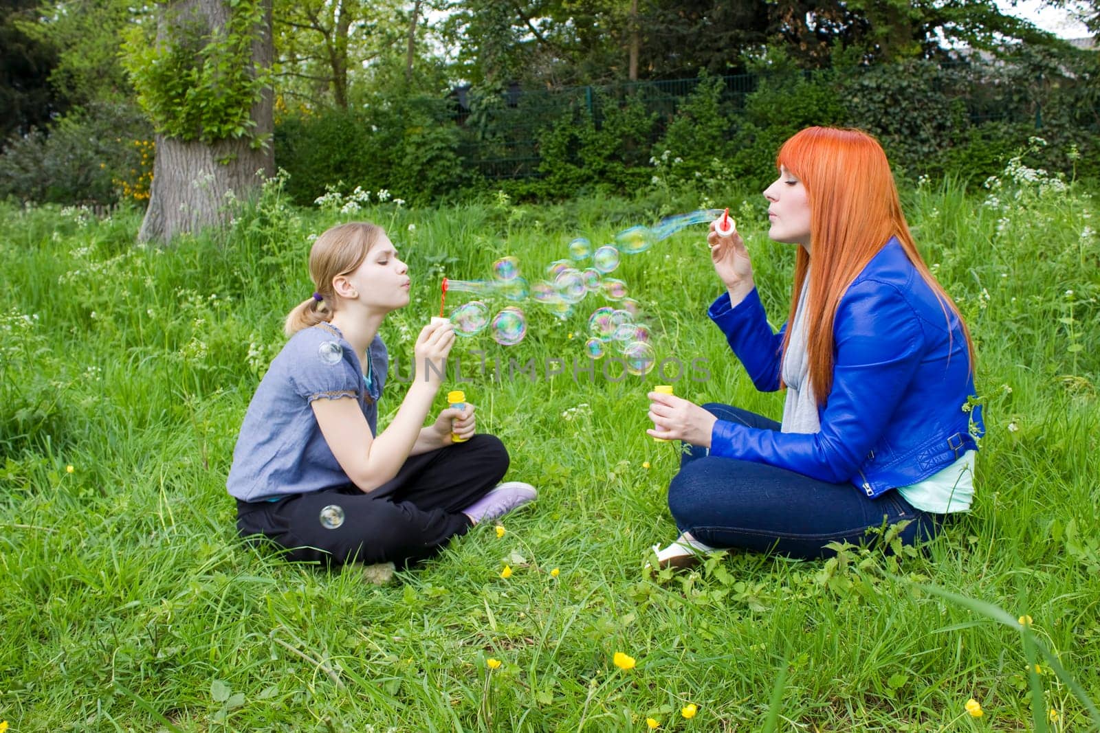 Little girl and young woman blowing soap bubbles