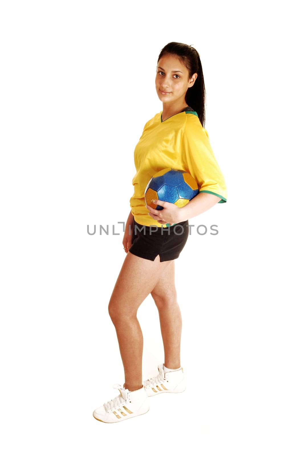 A teenage girl standing in profile, in a soccer uniform and holding the ball, with her long black hair for white background.
