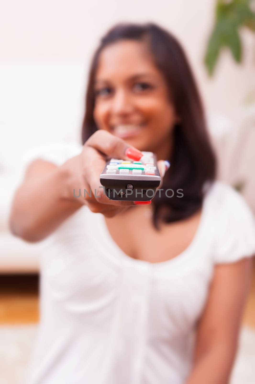 Young beautiful indian woman using a a tv remote controller