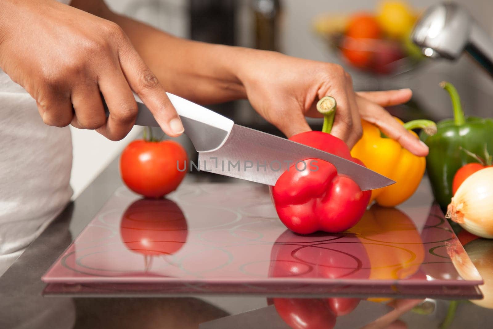African  American womans hand slicing a red pepper