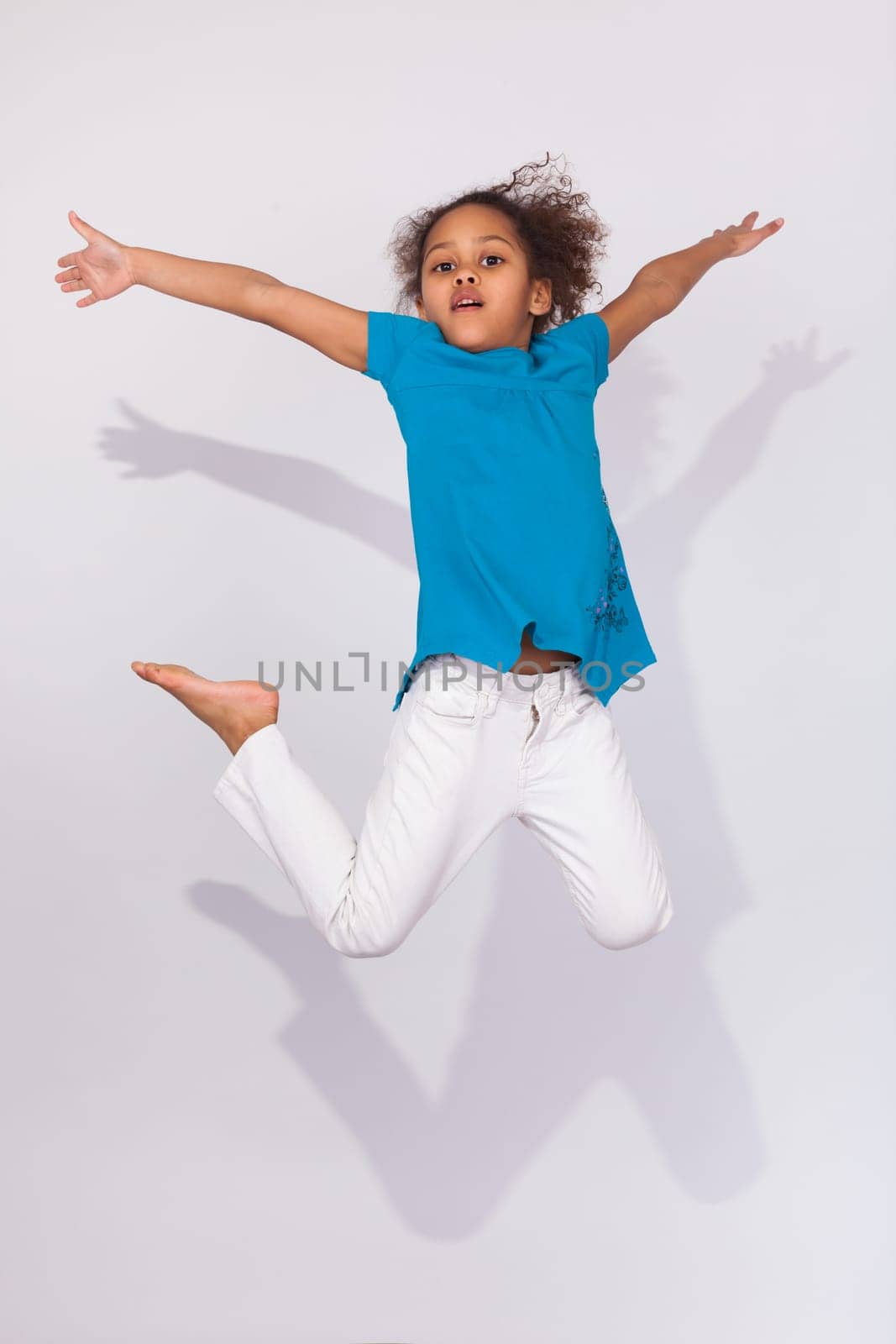 Portrait of cute Young African American girl jumping, over gray background