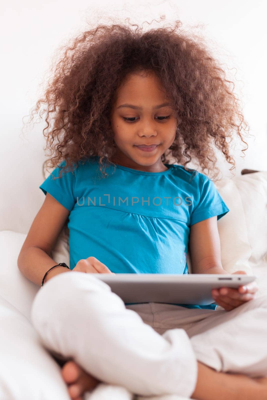 Little african asian girl seated on the couch using a tablet  pc