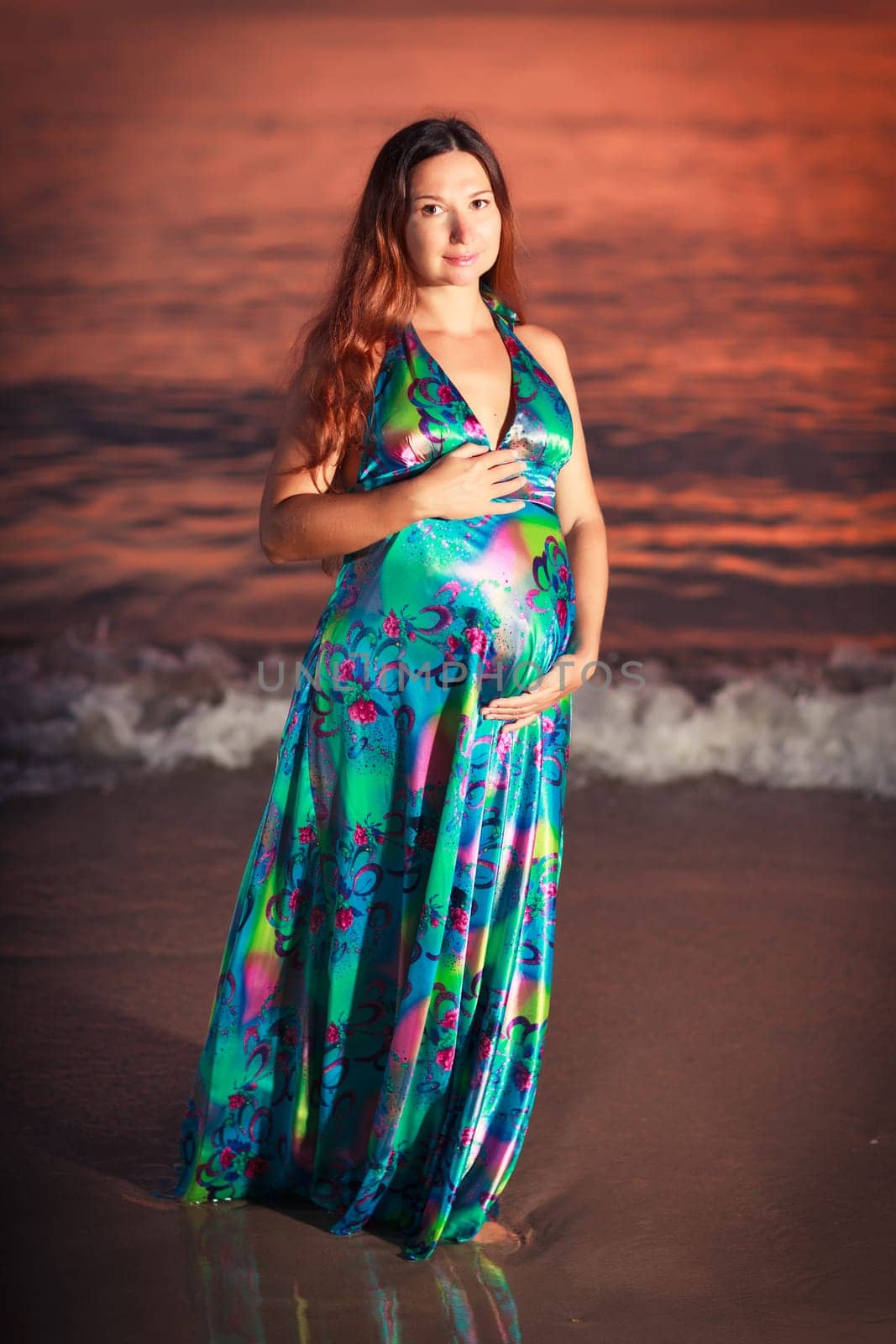 Beautiful pregnant woman at sunrise near the sea
