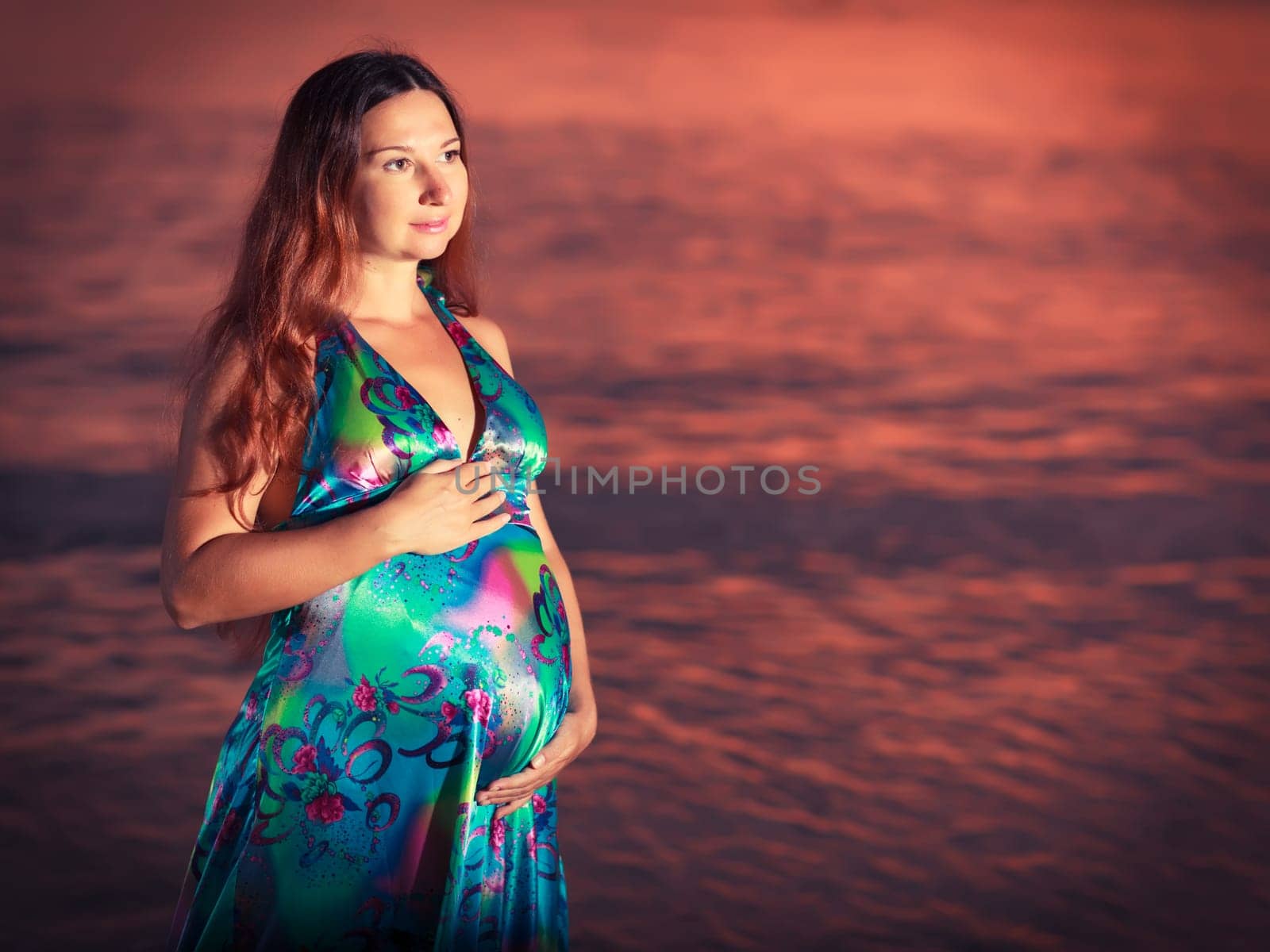 Beautiful pregnant woman at sunrise near the sea