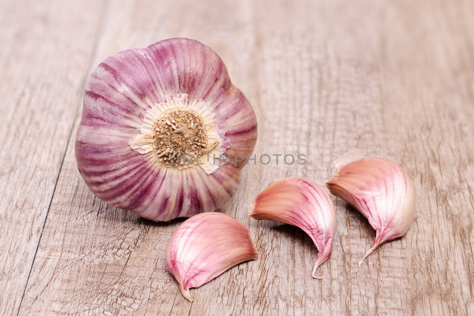 Garlic with three cloves of garlic on an old wooden board