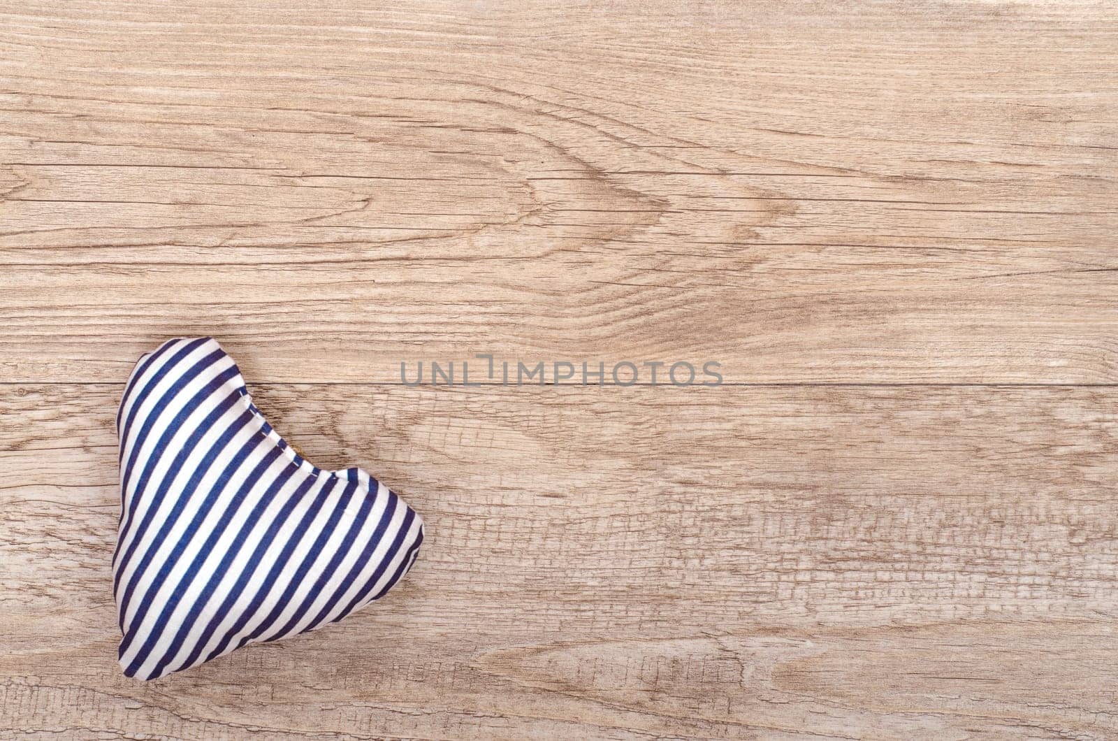 Blue and white striped heart made of fabric on weathered wood