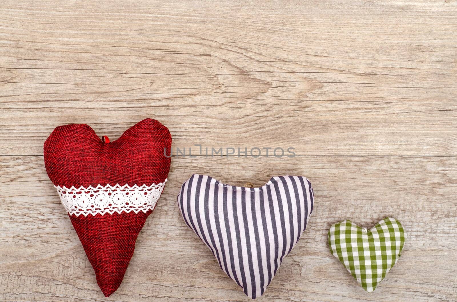 Weathered wooden board and three hearts made of fabric