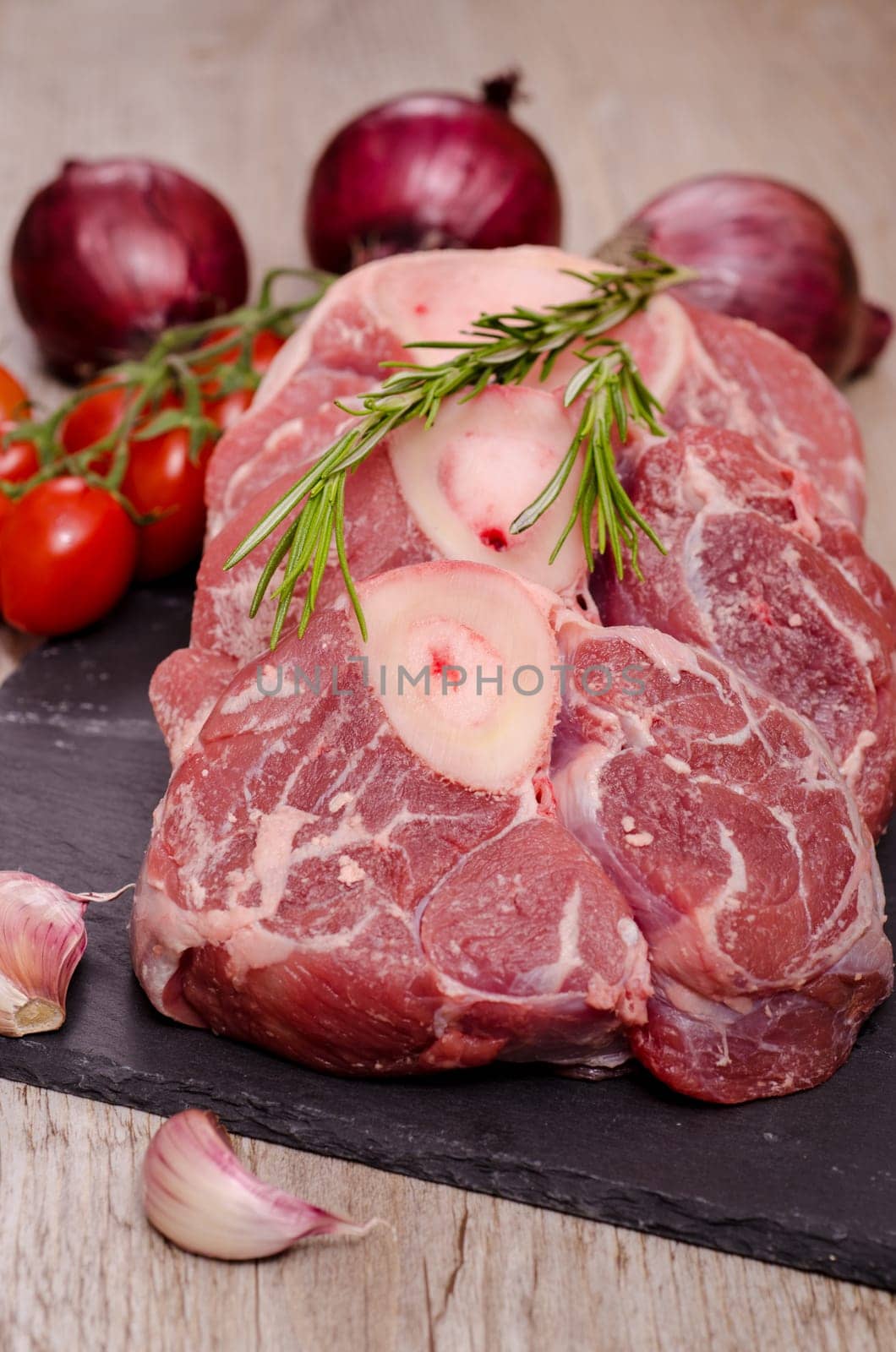 Raw veal leg slices for Italian osso buco with red onions