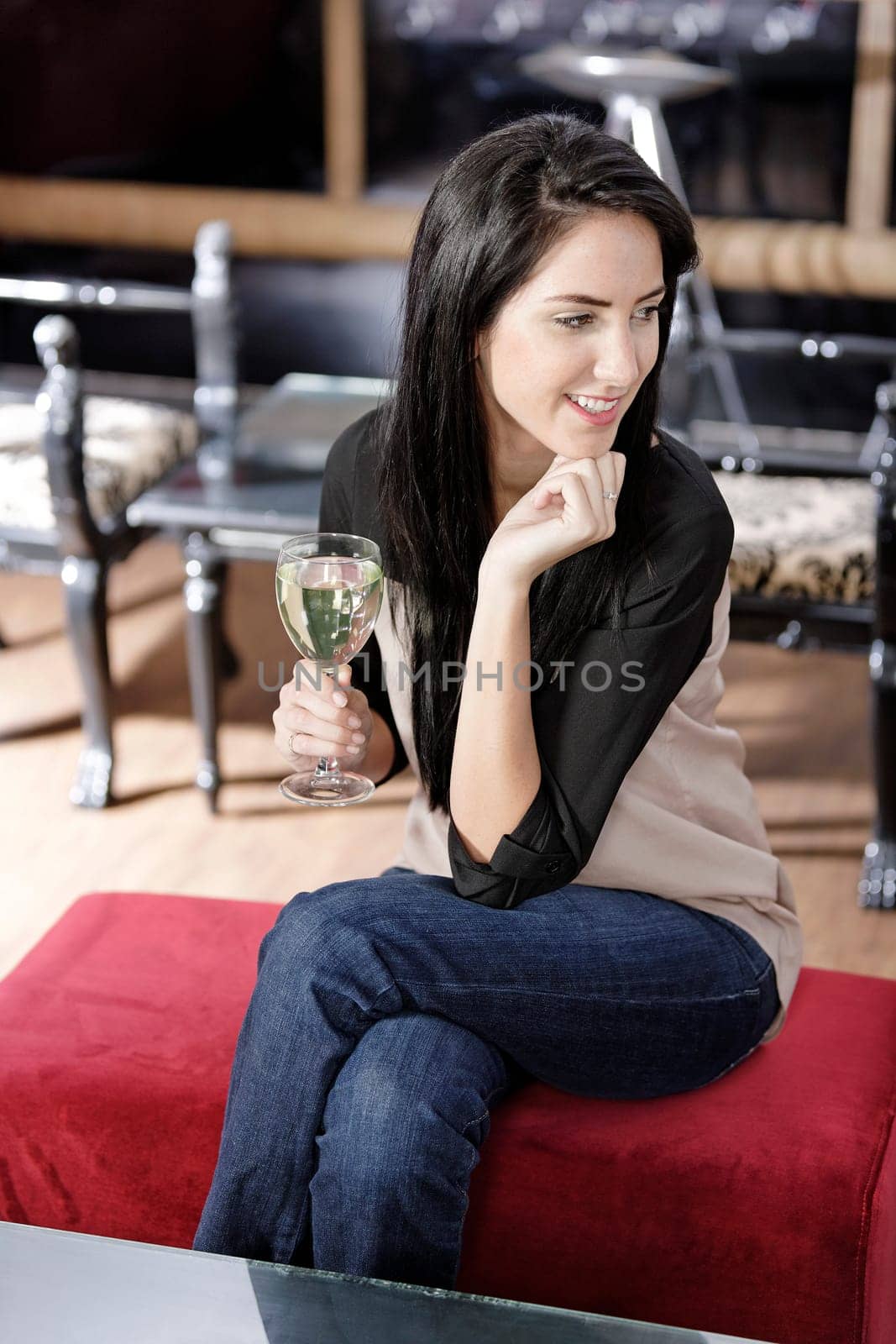 Attractive young woman enjoying a glass of white wine in a wine bar.