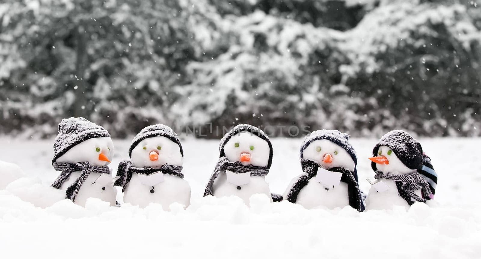 Little snowmen in a group carol singing in the snow