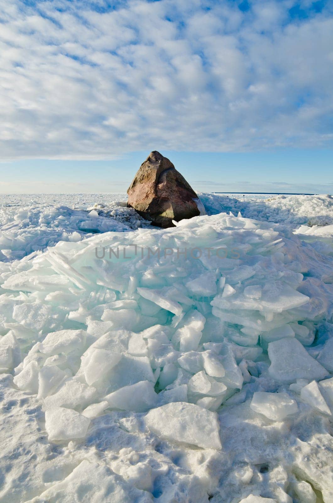 Big stone in the ice on the Baltic Sea coas