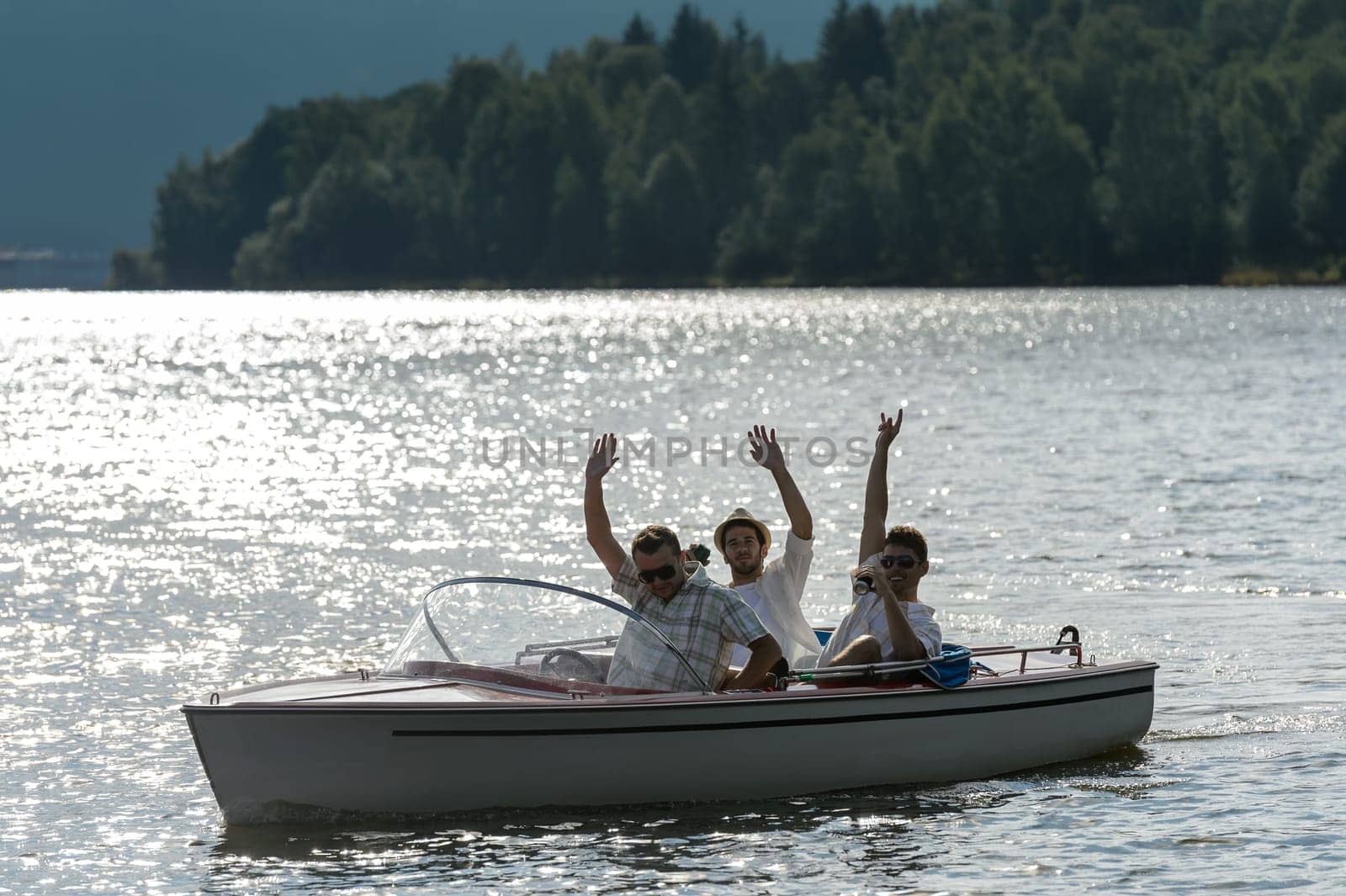 Silhouette of waving young men sitting in motorboat